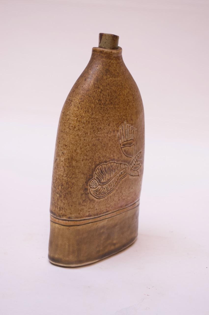 Keramischer Krug mit Keramikstopfen in einer tiefen Ocker-/Dijon-Farbe mit eingeritztem Dekor. 
Signiert 