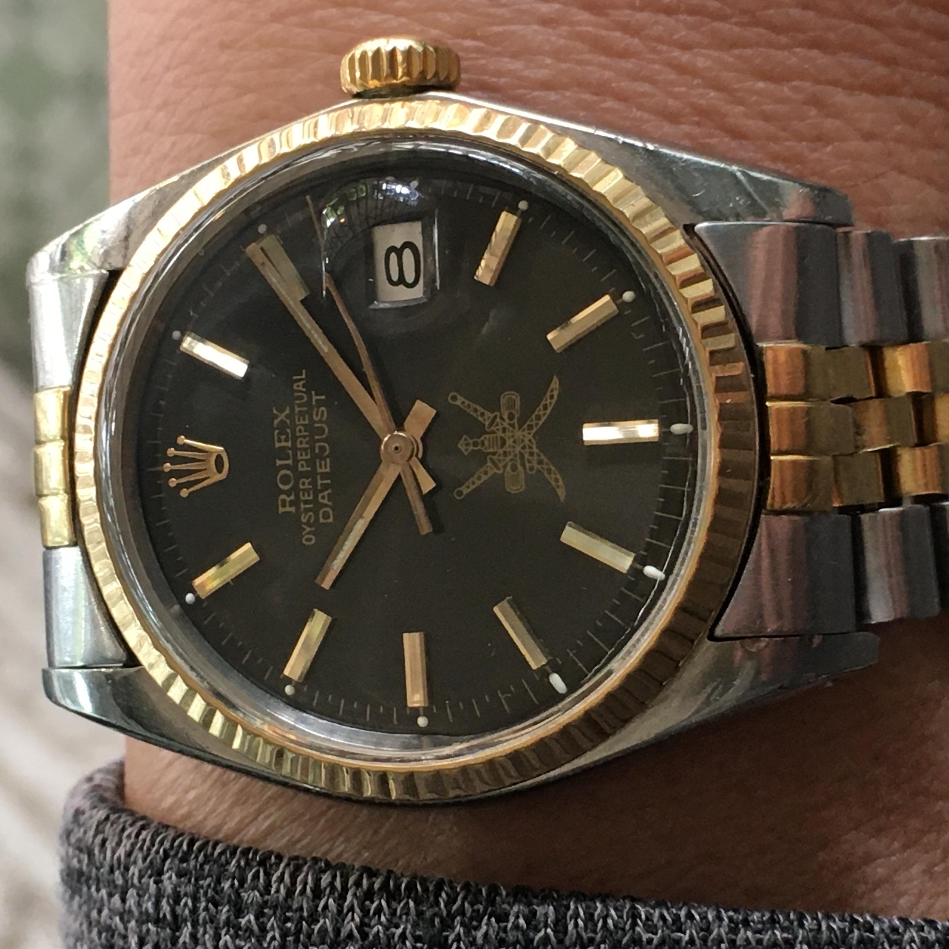 Dies ist ein Jahrgang 1974 Rolex Datejust Armbanduhr für Männer. Sie besitzt ein 36-mm-Edelstahlgehäuse mit einer goldenen geriffelten Lünette und ein schwarzes Khanjar-Zifferblatt mit mehreren Zeigern und einer 12-Stunden-Anzeige. Die Uhr hat ein