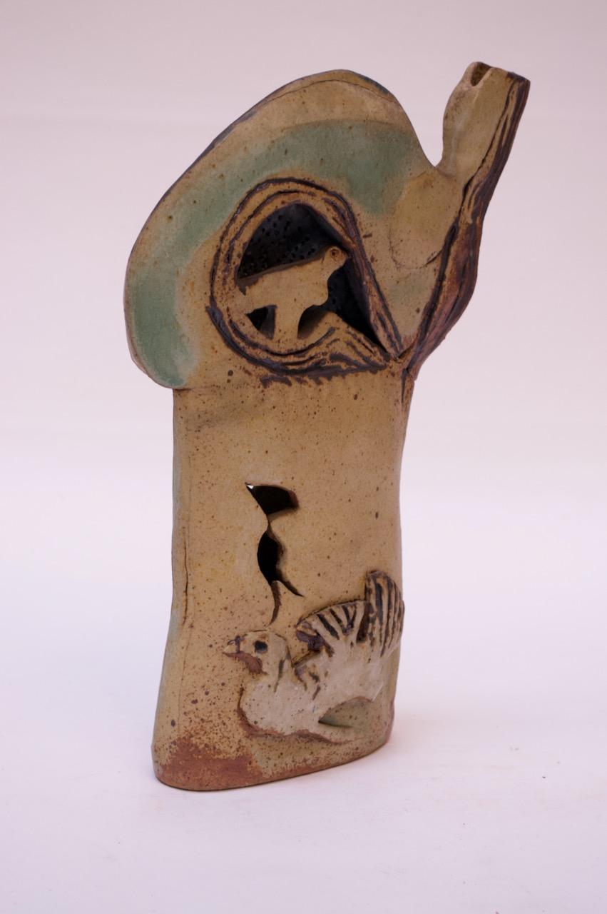 Impressive stoneware sculpture in matte sepia with pops of blue and green.
Interesting form, with bird motifs incorporating cut outs and open exposures as compositional constructs.
Signed 