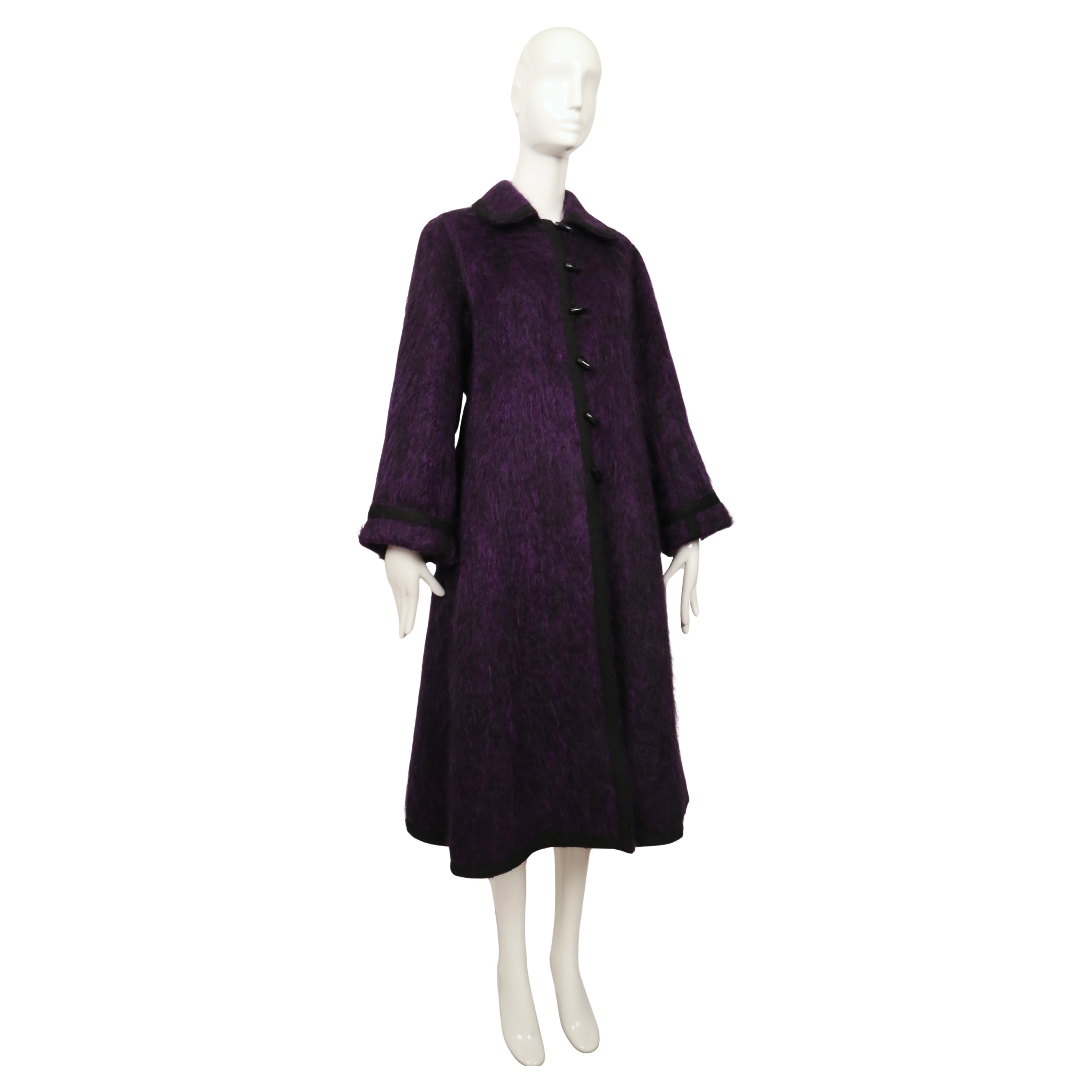 Dieser seltene Mantel von Yves Saint Laurent aus dem Herbst 1974 ist aus einer tief violett-lila gebürsteten Wolle mit einer weichen, strukturierten Oberfläche gefertigt. Es hat eine klare A-Linienform, die an den Schultern leicht ausgestellt ist,