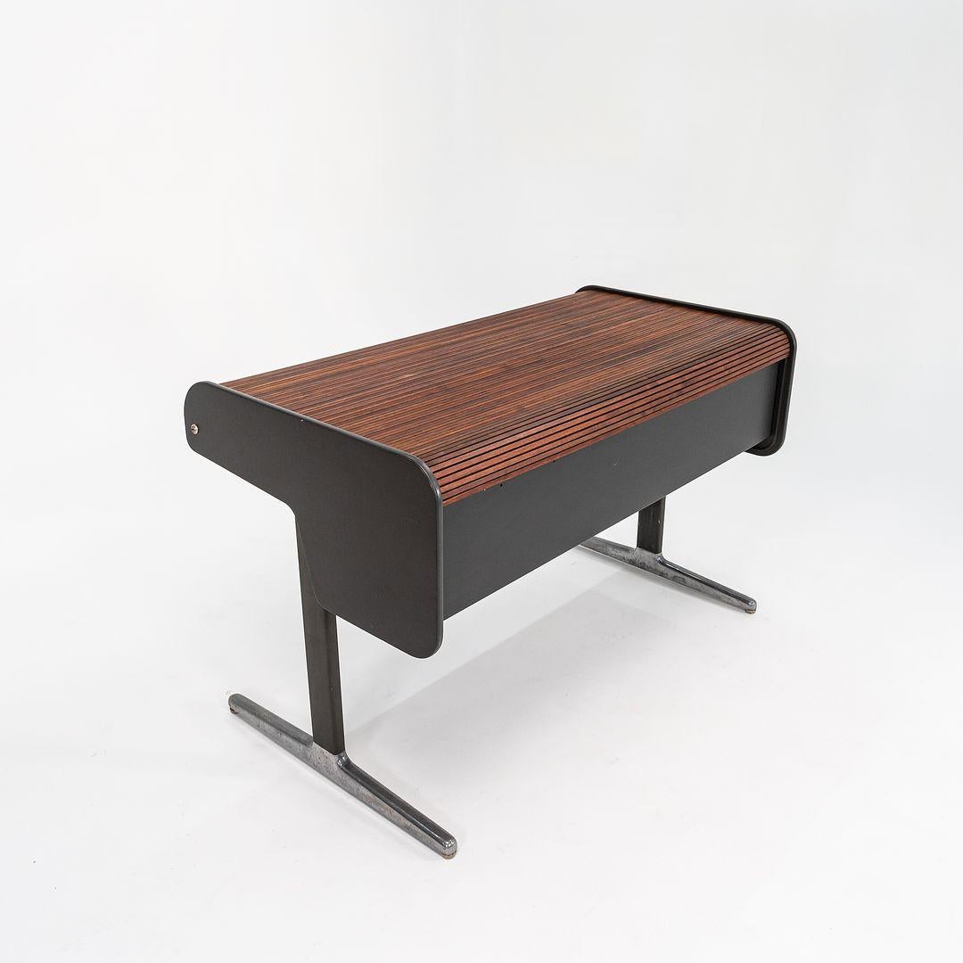 This is a Herman Miller Action Office II Series roll-top desk, designed by George Nelson in 1965. This example dates to 1975 and is dated as such. The piece features a rich walnut-veneered tambour, and has a cast aluminum and tubular steel base. It