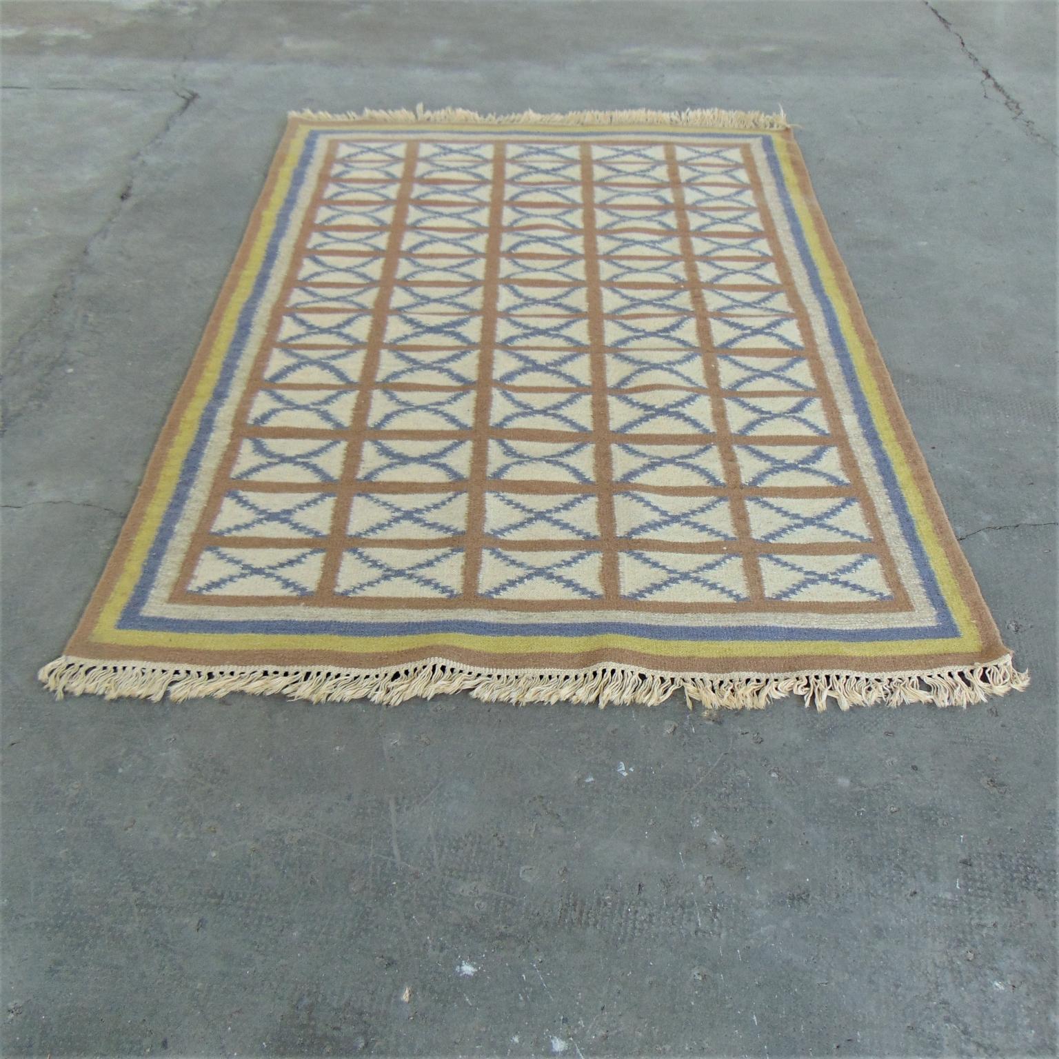 Dieser alte Teppich wurde Mitte der 1970er Jahre aus Indien nach Italien importiert. Es ist handgewebt, mit einer weichen Mischung aus warmen Farben wie Gelb und Hellbraun auf einem elfenbeinfarbenen Hintergrund, der durch ein blaues Muster