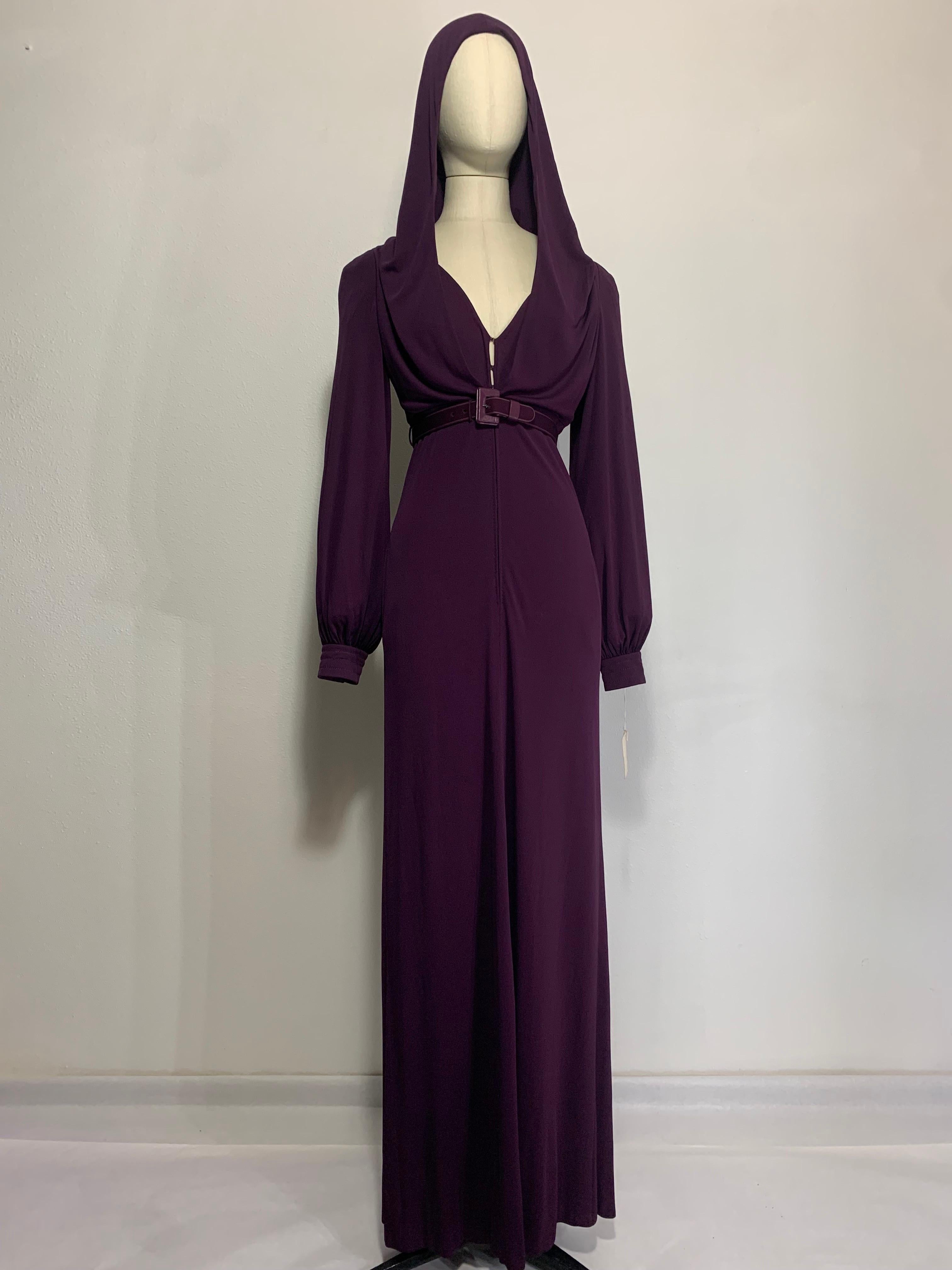 A dramatic and rare 1975 James Galanos aubergine rayon matte jersey gown with Empire belted waistline, full cuffed sleeves and a gorgeous loosely draped hood! Channel your inner Grace in this spectacular look. Body of gown is double layered. Center