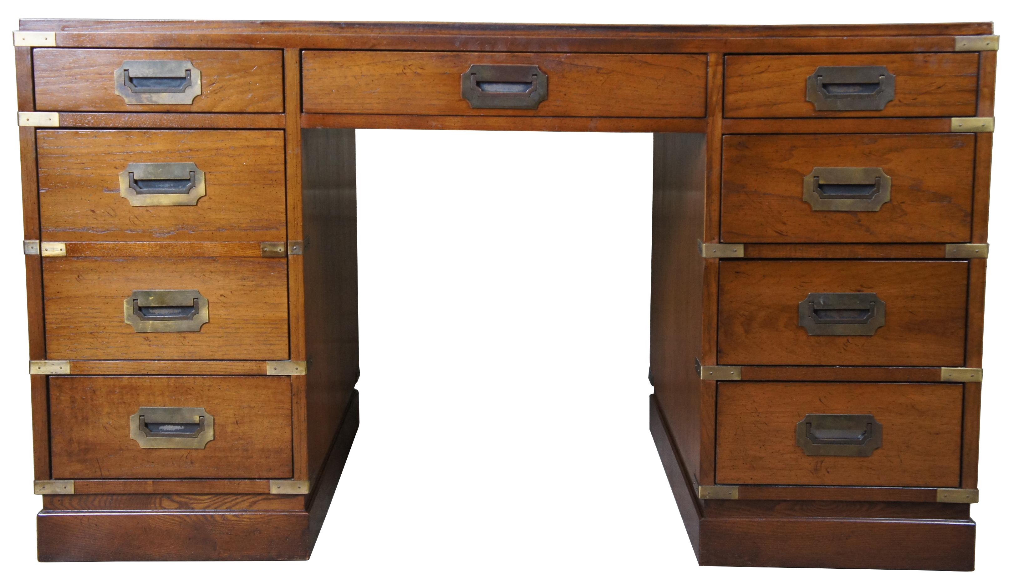 Sligh oak and leather top writing desk. Made in August of 1975. Features Campaign styling with brass applied mounts and handles. Opens to seven standard drawers in addition to one file drawer.
  