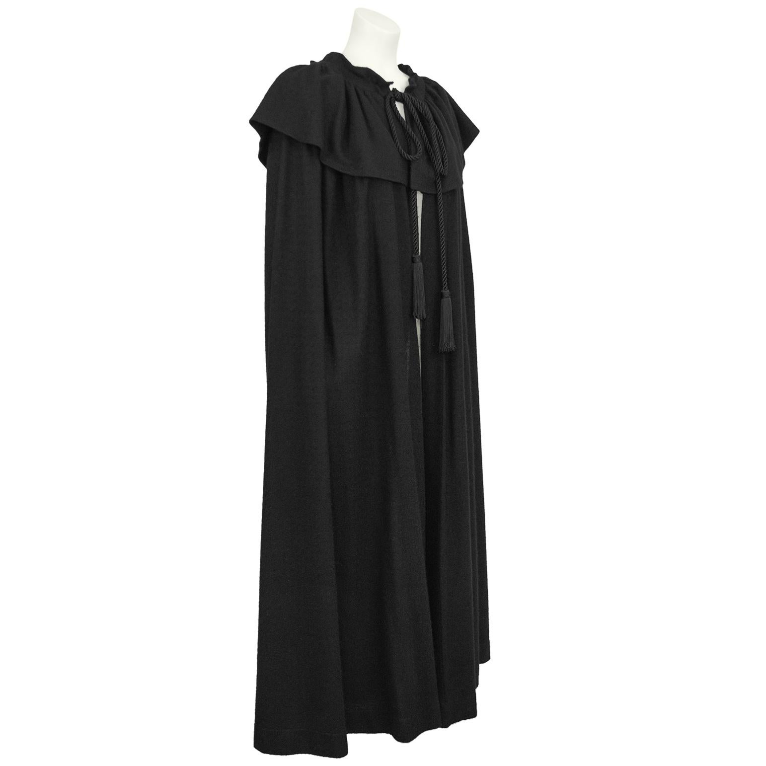 Vintage YSL Rive Gauche black wool cape from 1976. Lightweight black wool cape with long silky tassel ended neck ties. The necktie runs through the neck casing and can gather the neck in. A narrow gathered collar has a deep shoulder length cape-let