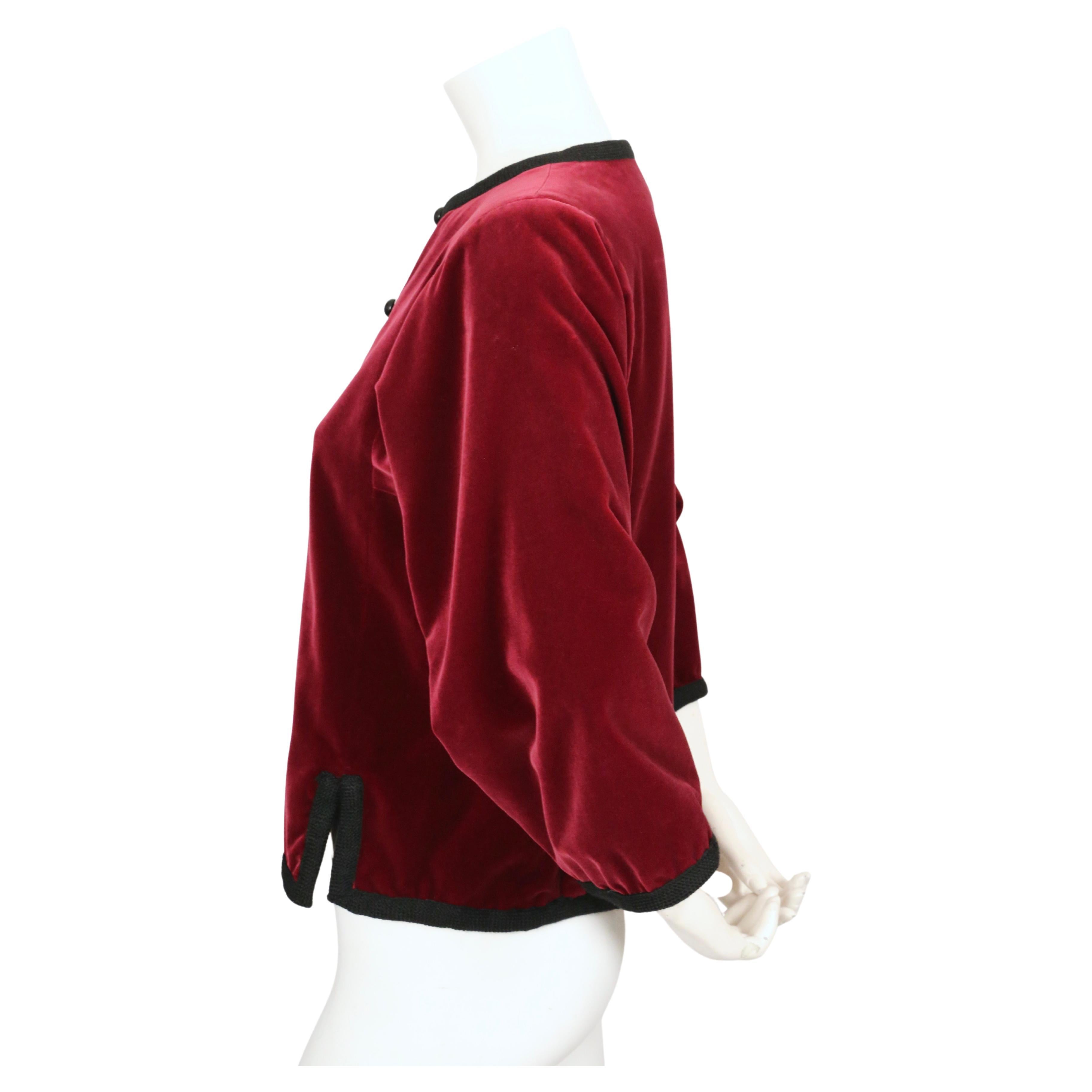 Rich burgundy, velvet jacket with black woven wool trim designed by Yves Saint Laurent dating to fall of 1976 as seen on the 'Ballet Russes' runway.  Jacket has full sleeves and slits a front his. Jacket size is unlabeled however it best fits a