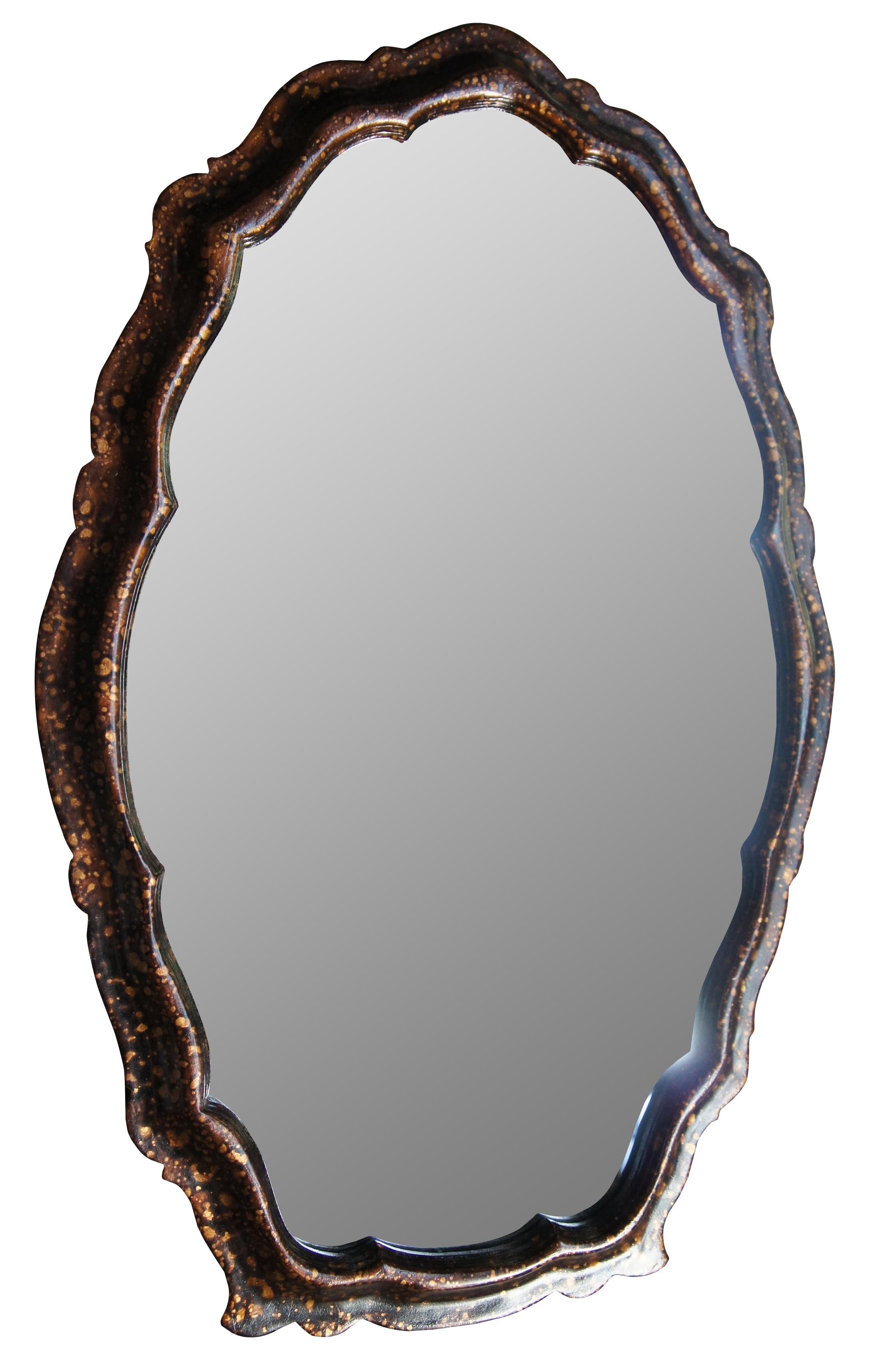 Vintage scalloped oval form wall hanging mirror featuring a painted tortoise shell finish in golds and browns.  Circa 1977