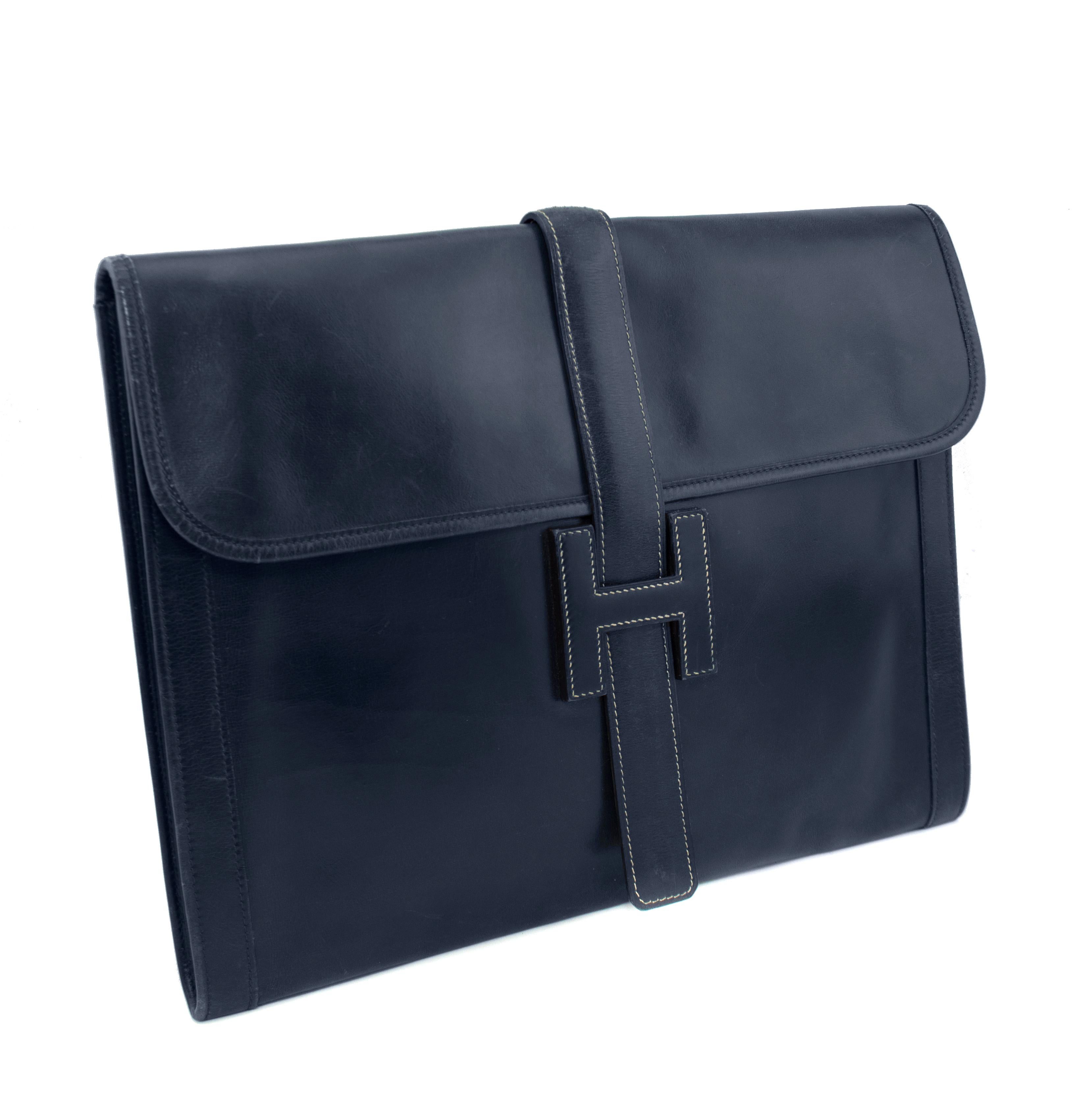 A classic that never goes out of the style, the Hermes Jige has been the perfect day-to-night clutch since it's creation in 1975. This 1977 navy leather version has the H style leather clasp on the front with a top flap opening. Finished with cream