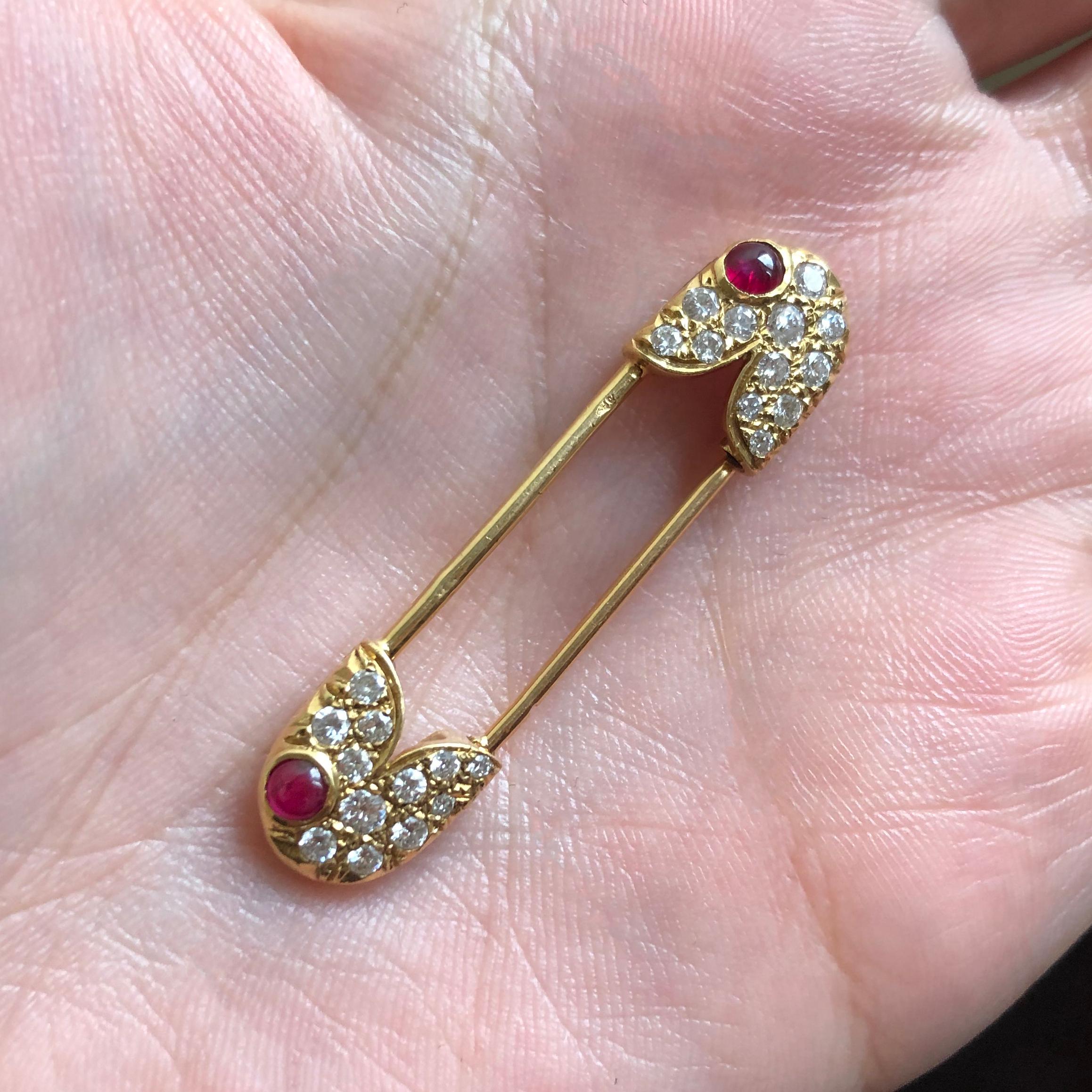 A cabochon ruby, diamond and 18 karat yellow gold safety pin, by Van Cleef & Arpels, 1978.

Signed VCA 78 and with VCA maker's mark. Stamped with copyright symbol and 750. Numbered and stamped with French hallmarks.