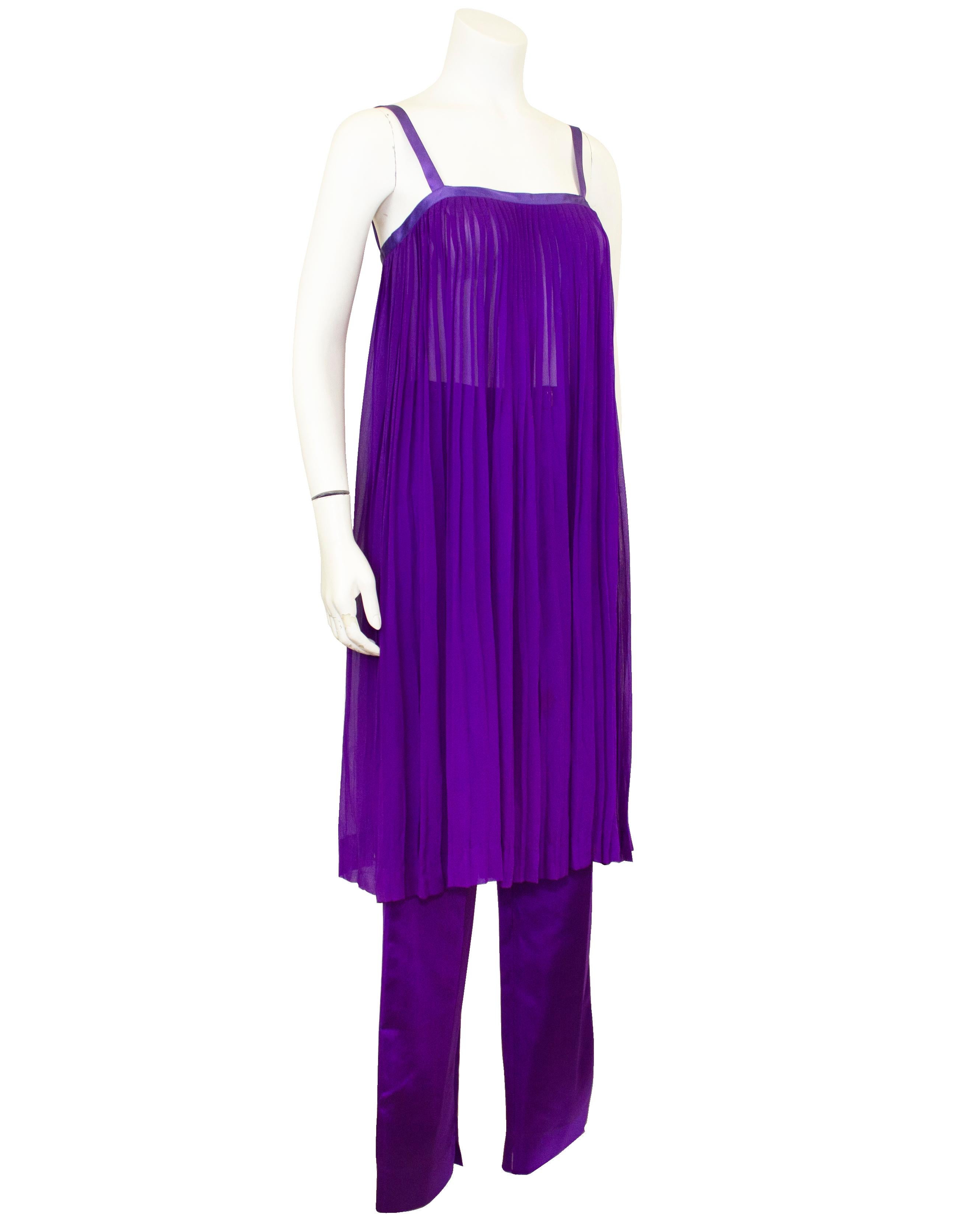 Vibrant jewel toned ensemble from Yves Saint Laurent’s “High Seas Chic” RTW Spring 1978 collection. Purple pleated silk georgette sleeveless tunic with matching purple satin trim. Silk satin high waisted straight plated leg pants. Belt waist on