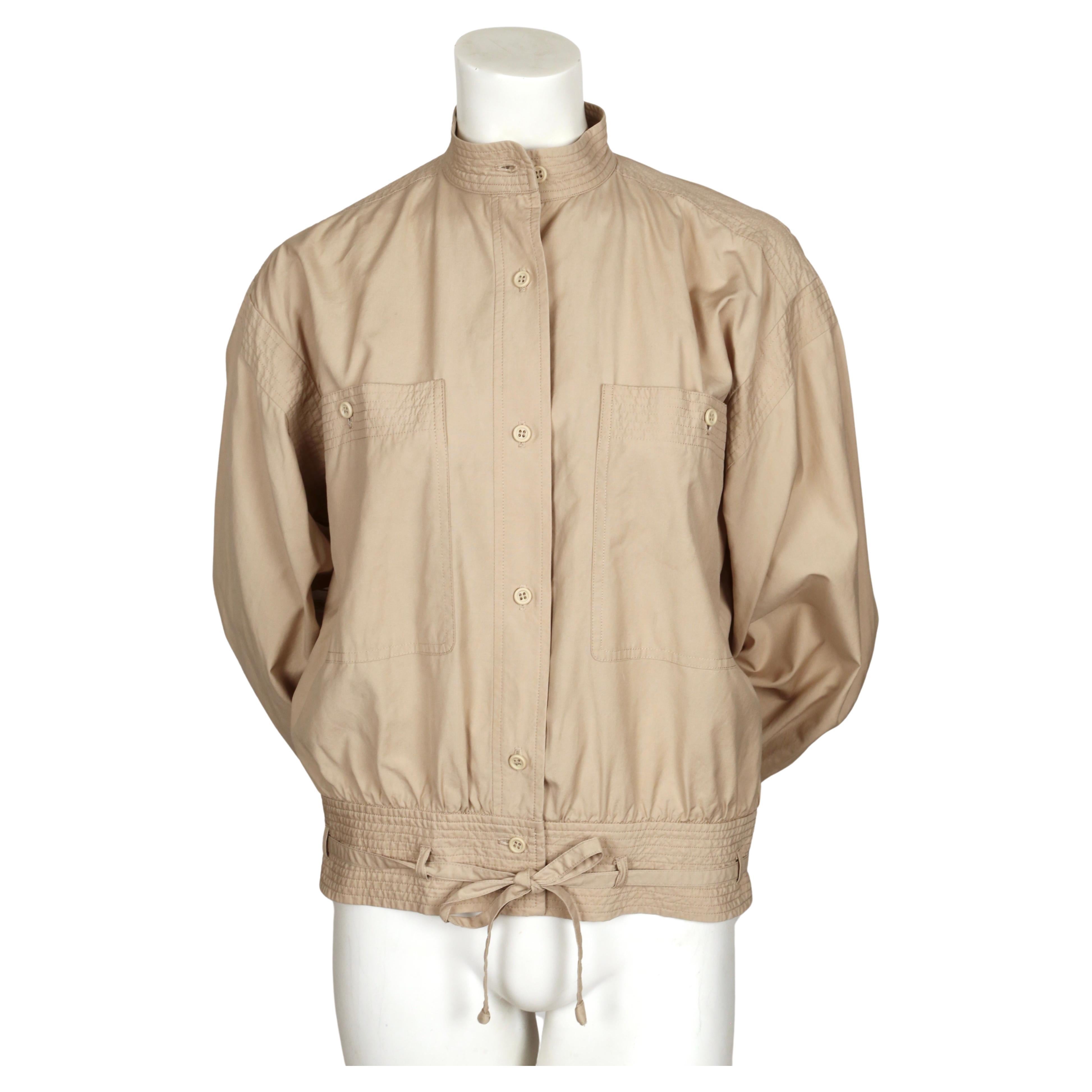 Tan, lighter-weight, cotton safari jacket with fitted band at hip and large chest pockets designed by Yves Saint Laurent rive gauche dating to 1978 exactly as seen on the spring runway. No size is indicated however this has an oversized fit and best