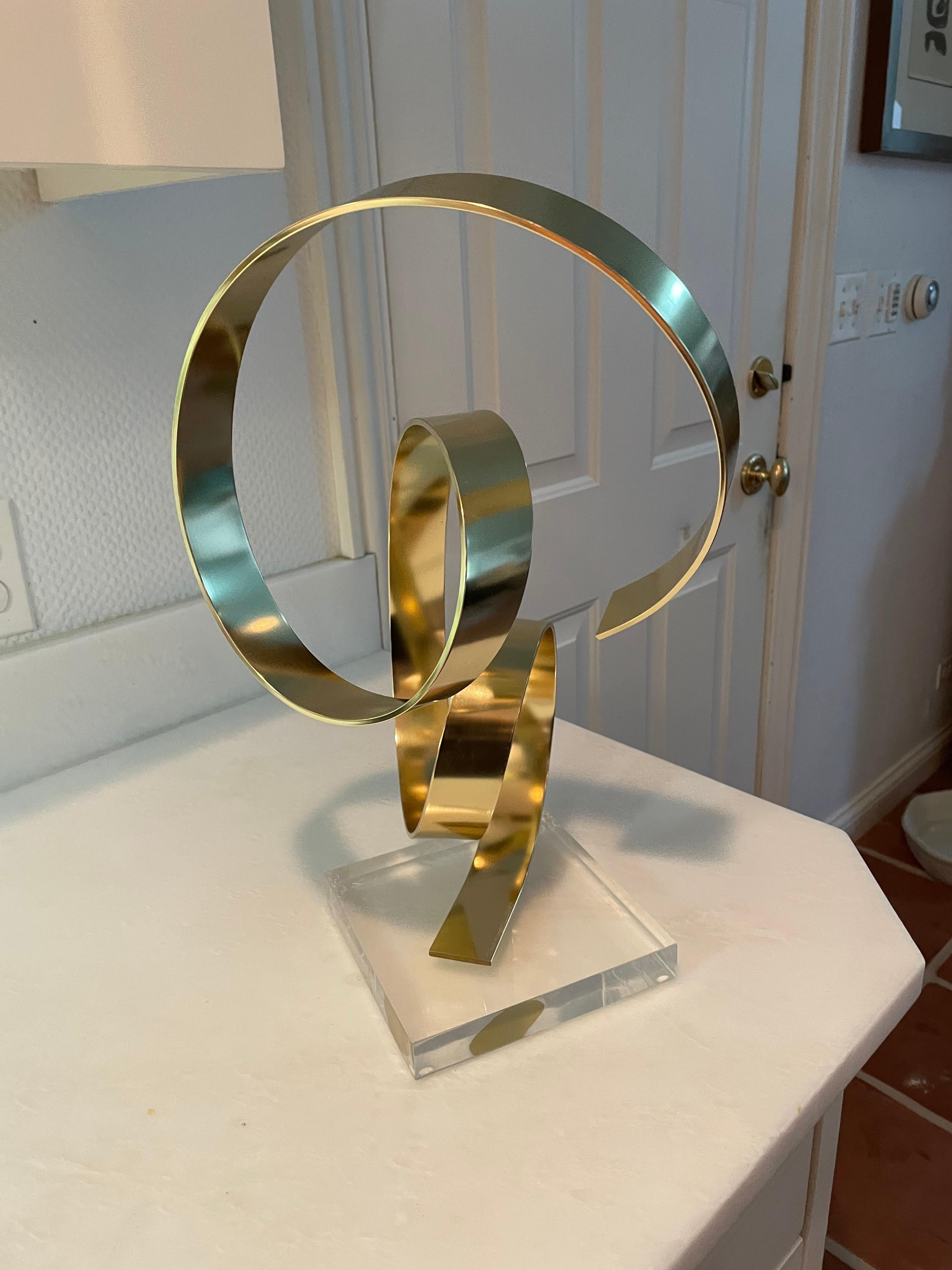 This is a lovely brass metal abstract sculpture by Dan Murphy in 1979 and is mounted on a lucite base.