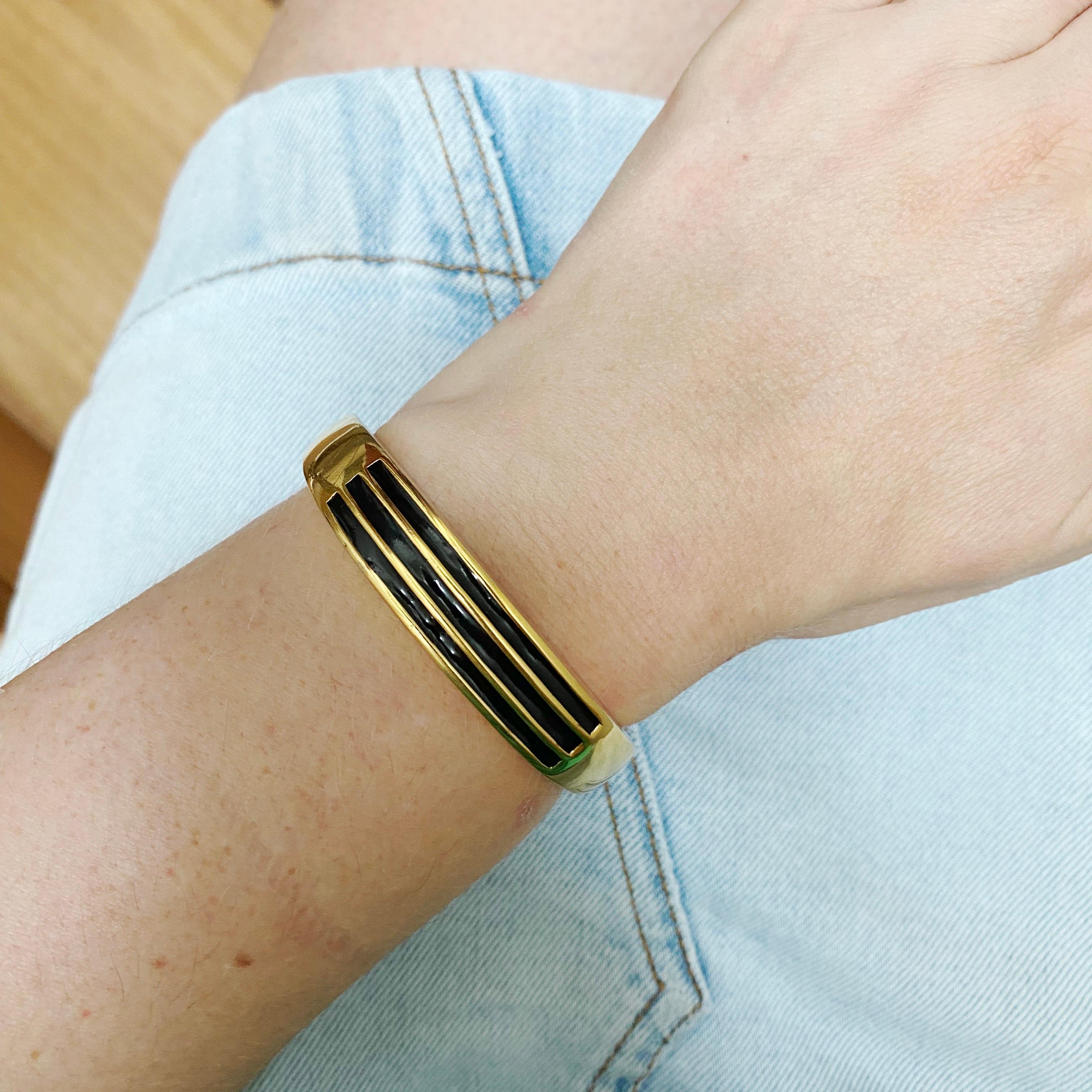Modernist style bangle by French designer, Givenchy. High polish goldtone metal with enamel detail. In good vintage condition.  A fantastic piece to style with contemporary clothing trends. 