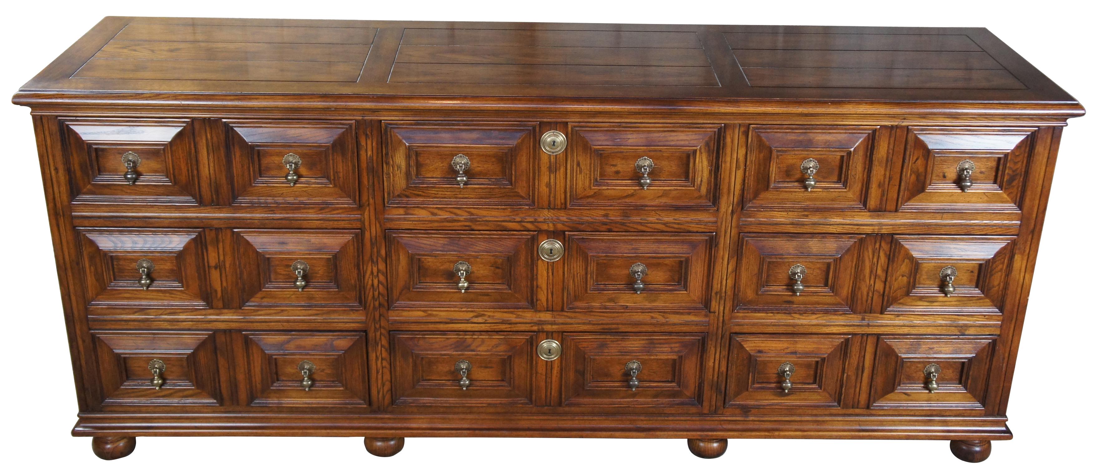 1979 Henredon folio 12 nine-drawer dresser. Made from oak with Classic 18th century English styling. Includes robust paneled drawer fronts with Victorian inspired knockers, brass key plates and bun feet.
   