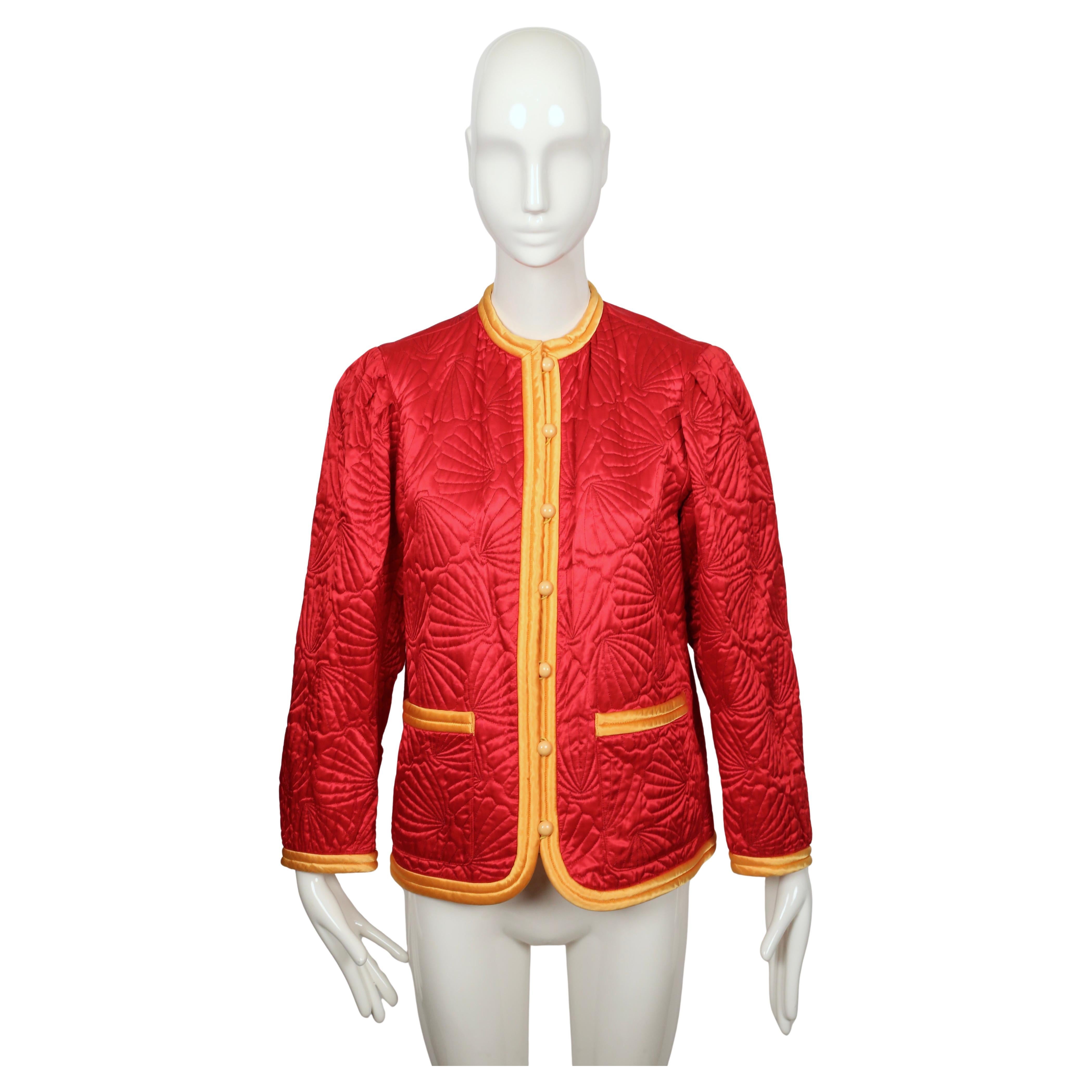 Superbe veste matelassée en satin rouge du défilé 1979 d'Yves Saint Laurent, à la coupe épurée et sans col, mettant en valeur le tissu. La surface est piquée d'un motif coquillage légèrement paddé qui accroche la lumière et donne à la veste un