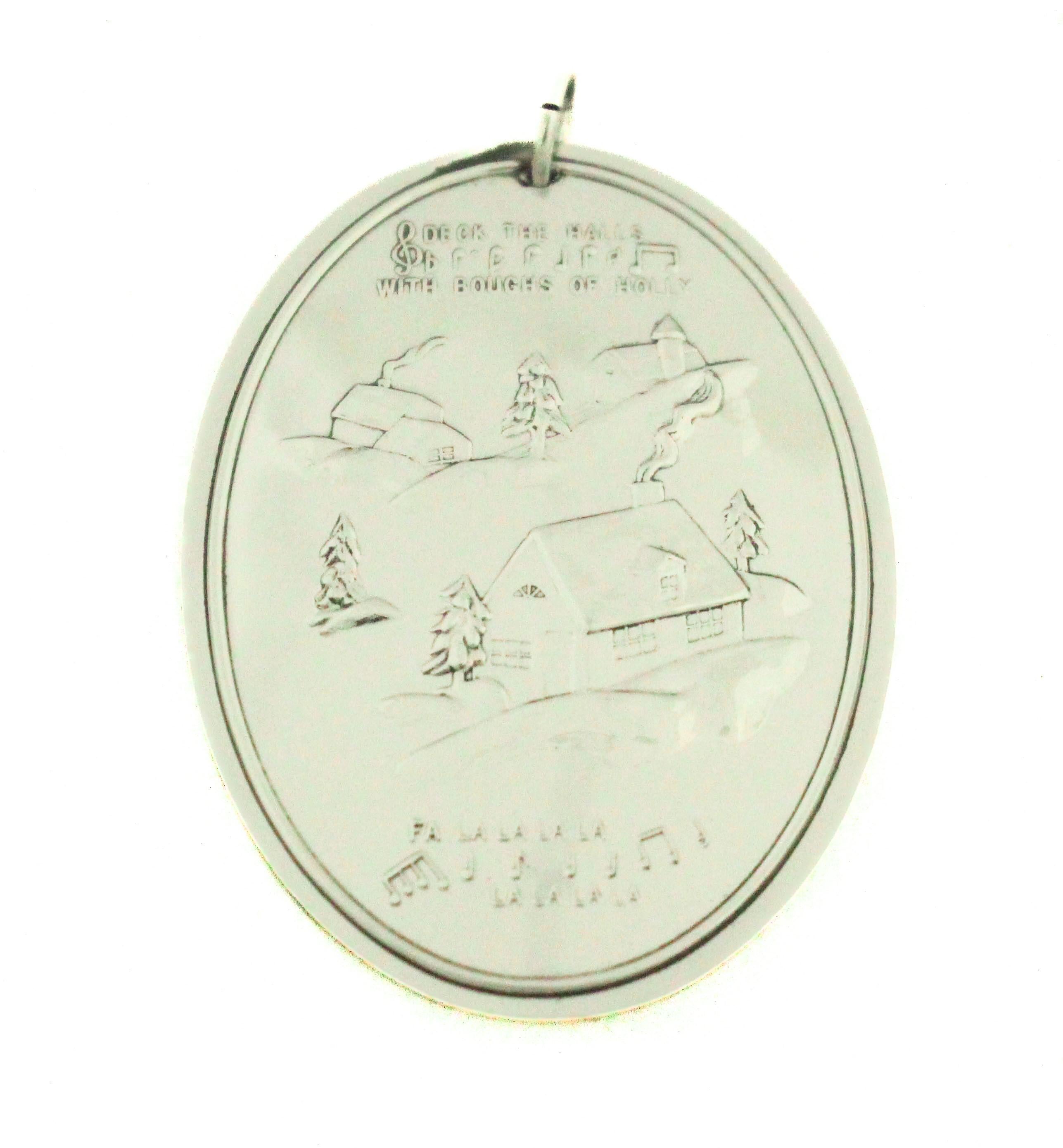 This charming 1979 sterling silver Christmas ornament by Towle Silversmiths beautifully captures the warmth and nostalgia of traditional holiday celebrations. Featuring a dual-sided design—one symbolic and one narrative—this piece exemplifies