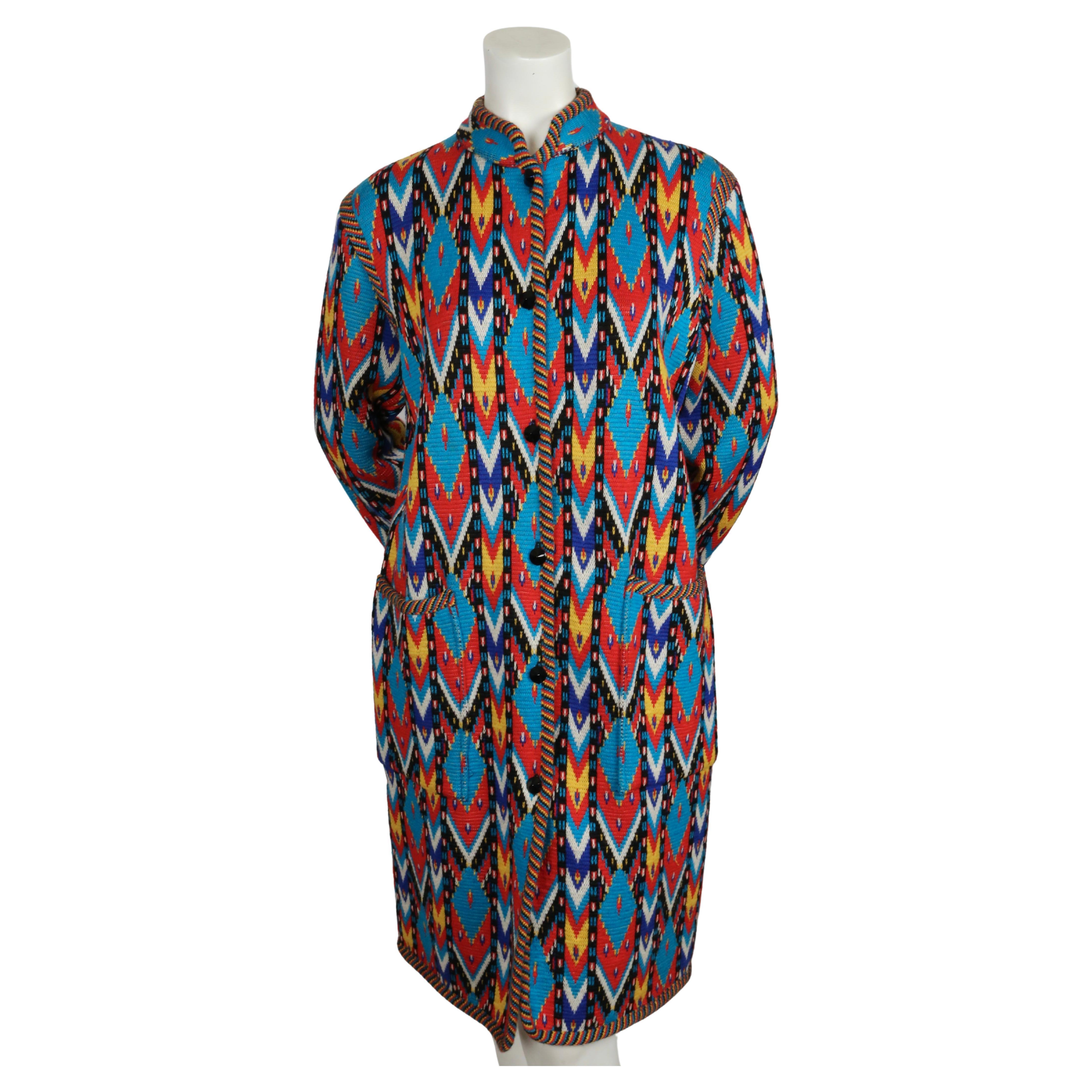 Multi-colored, Ikat patterned, woven wool sweater coat  with patch pockets designed by Yves Saint Laurent dating to fall of 1979. Labeled a French size 42. Approximate measurements (unstretched): shoulder 17