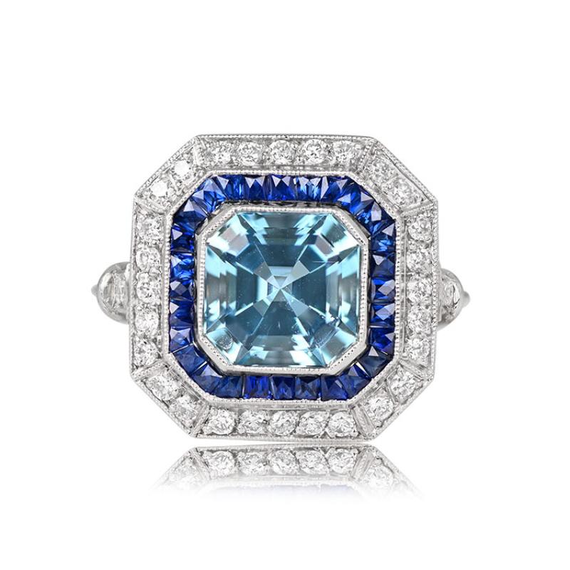 A platinum ring showcasing a 1.97-carat Asscher-cut aquamarine encircled by a dual halo. The first halo consists of calibrated French cut sapphires, while the second halo is formed by round brilliant cut diamonds. The shoulders are adorned with