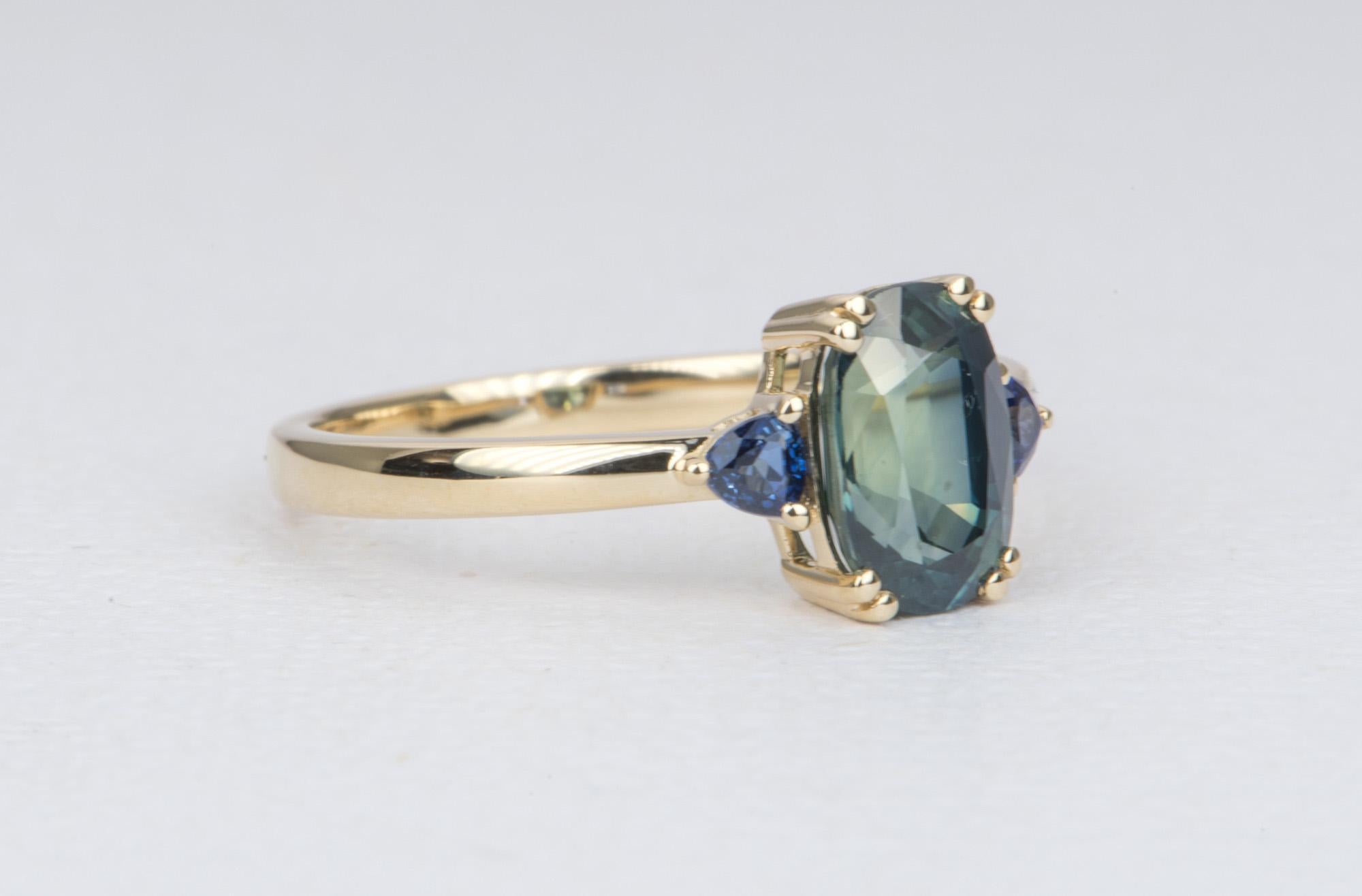 ♥  This is a modern engagement ring with a beautiful oval/cushion cut blue sapphire in the center, flanked by two trillion-shaped sapphires on the side. The corners of the main sapphire are set with double prongs for a unique look.
♥  The center