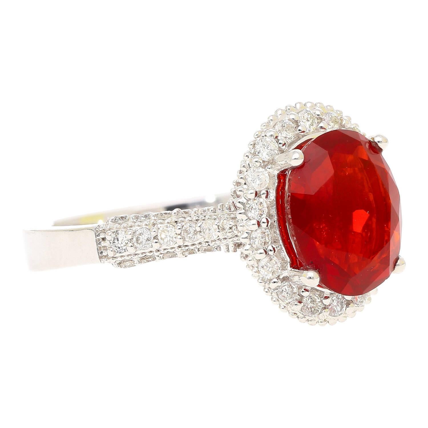 Questo splendido anello da cocktail presenta un vibrante opale dal taglio ovale incastonato nell'oro bianco 14 carati e incorniciato da un'abbagliante aureola di diamanti. L'intricato gambo in filigrana aggiunge eleganza e dimensione alla sua