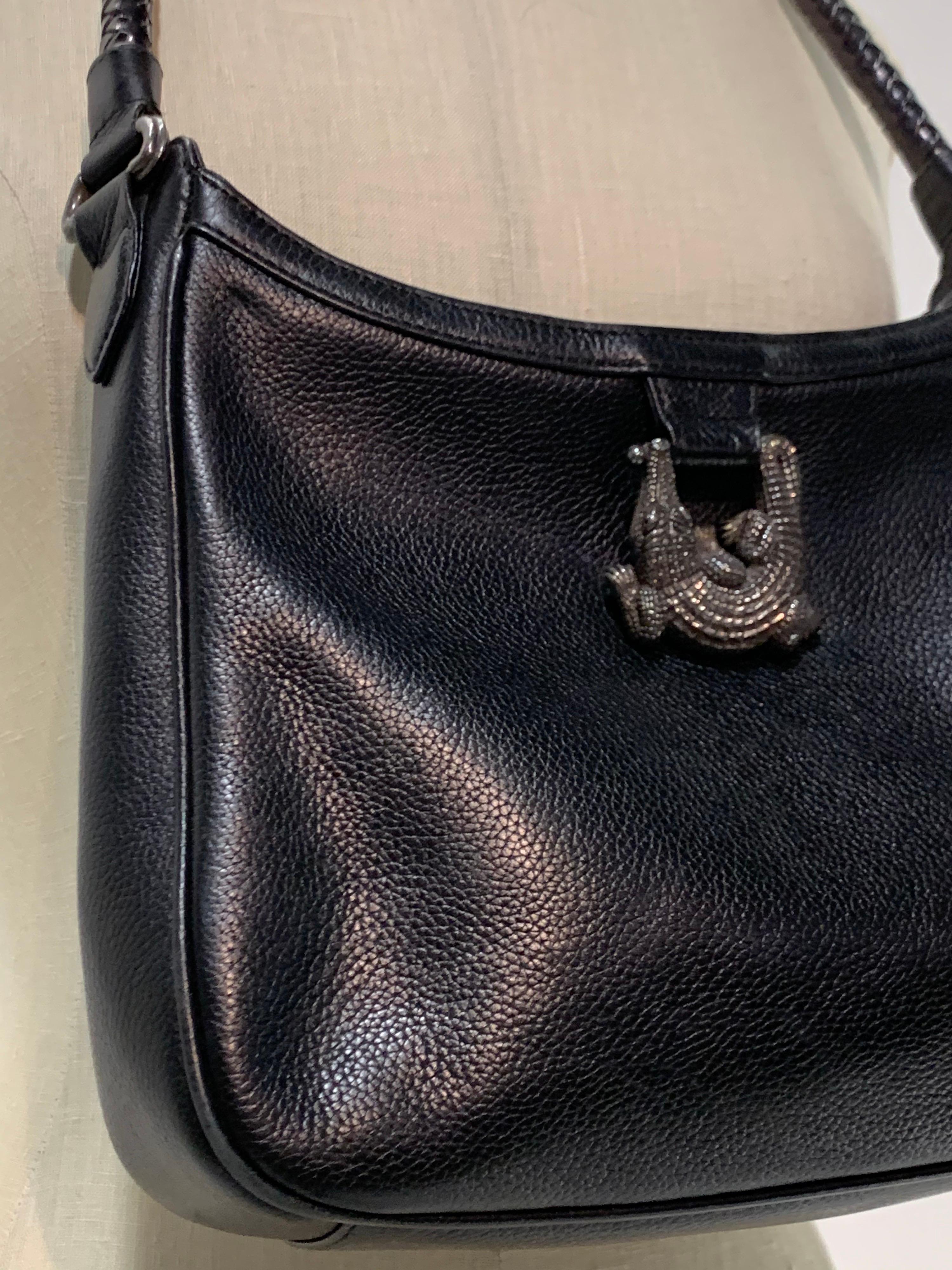A simple 1980s Barry Kieselstein-Cord black pebbled leather satchel bag with large signature silver alligator hardware. Braided leather handle. Zipper closure. 