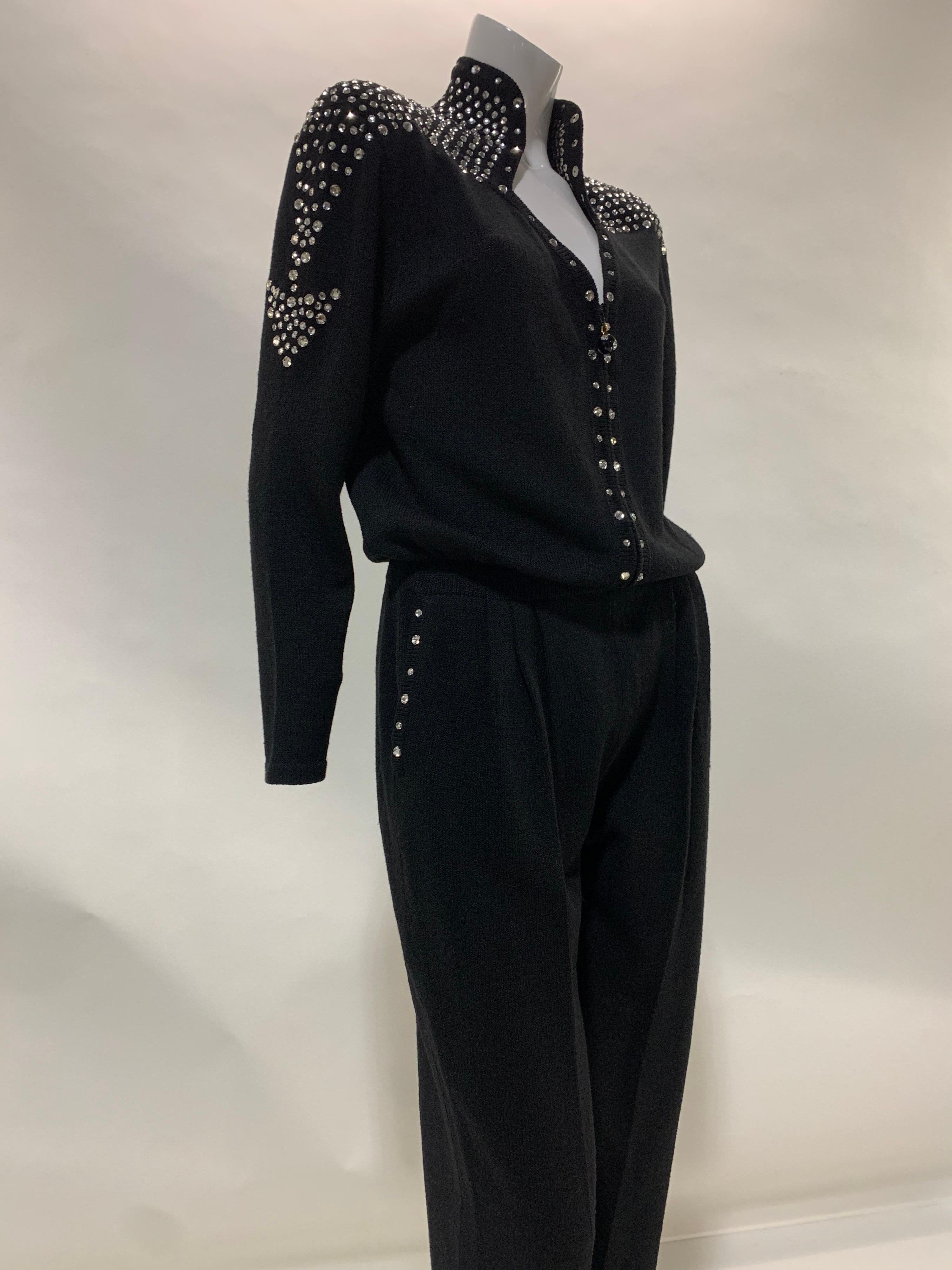 A fabulous 1980s black rayon knit jumpsuit with stovepipe legs padded structured shoulders that are heavily embellished with rhinestone arrows traveling over shoulder yolk and down upper arm. Front zipper. Size 8-10.