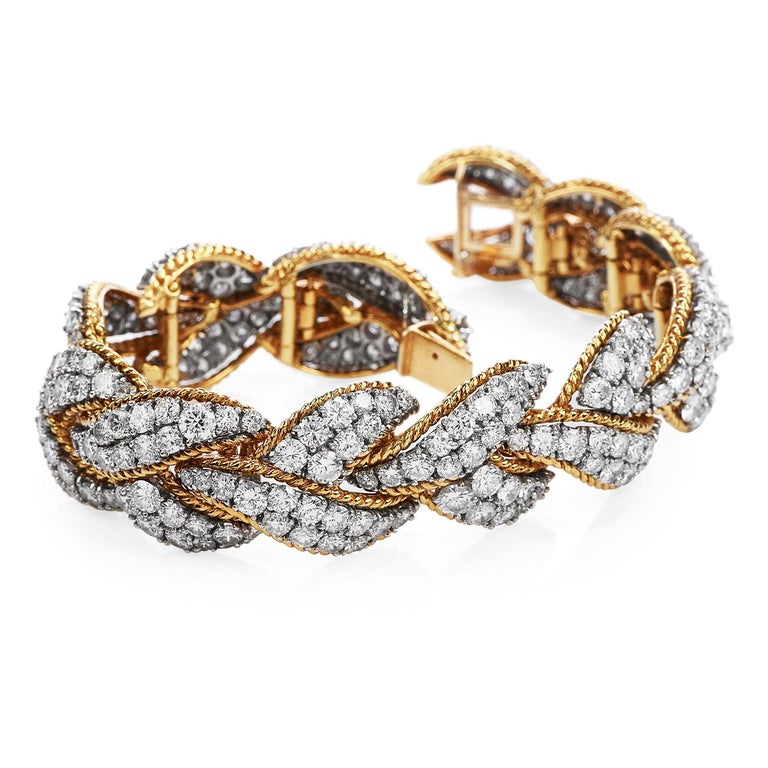 This Intricate yet Sparkly Piece is crafted in solid 18-karat Yellow & White Gold,

weighing 83.7 Grams and measuring 6 ½” around the wrist x 18mm wide.

Composed of a braided design of 18K Yellow Gold &  elongated cluster design textured white gold