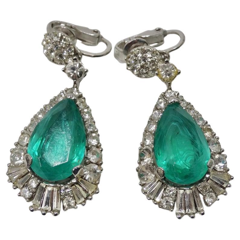 Stunning 1980s drop earrings featuring the most beautiful blue/green stones at the center! Timeless drop style earrings give way to an array of different sized baguette and round silver rhinestones. The focal point of the earrings is the gorgeous