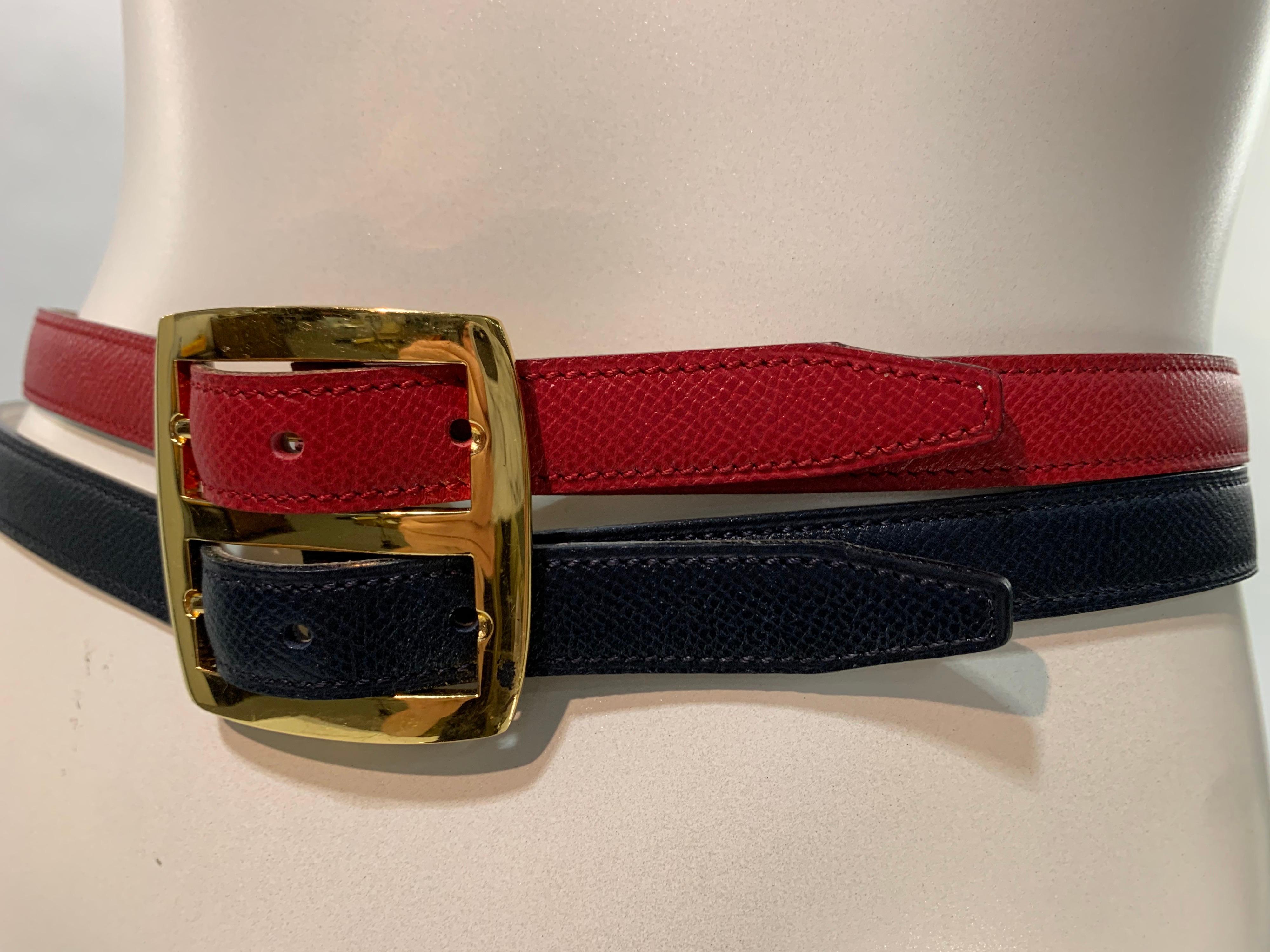 A fabulously useful and versatile 1980s Hermes reversible double leather belt: one side is a stamped lizard finish in Hermes' signature red and navy blue and the other is chestnut brown and white. Gold side-by-side double buckle. Size Small.
