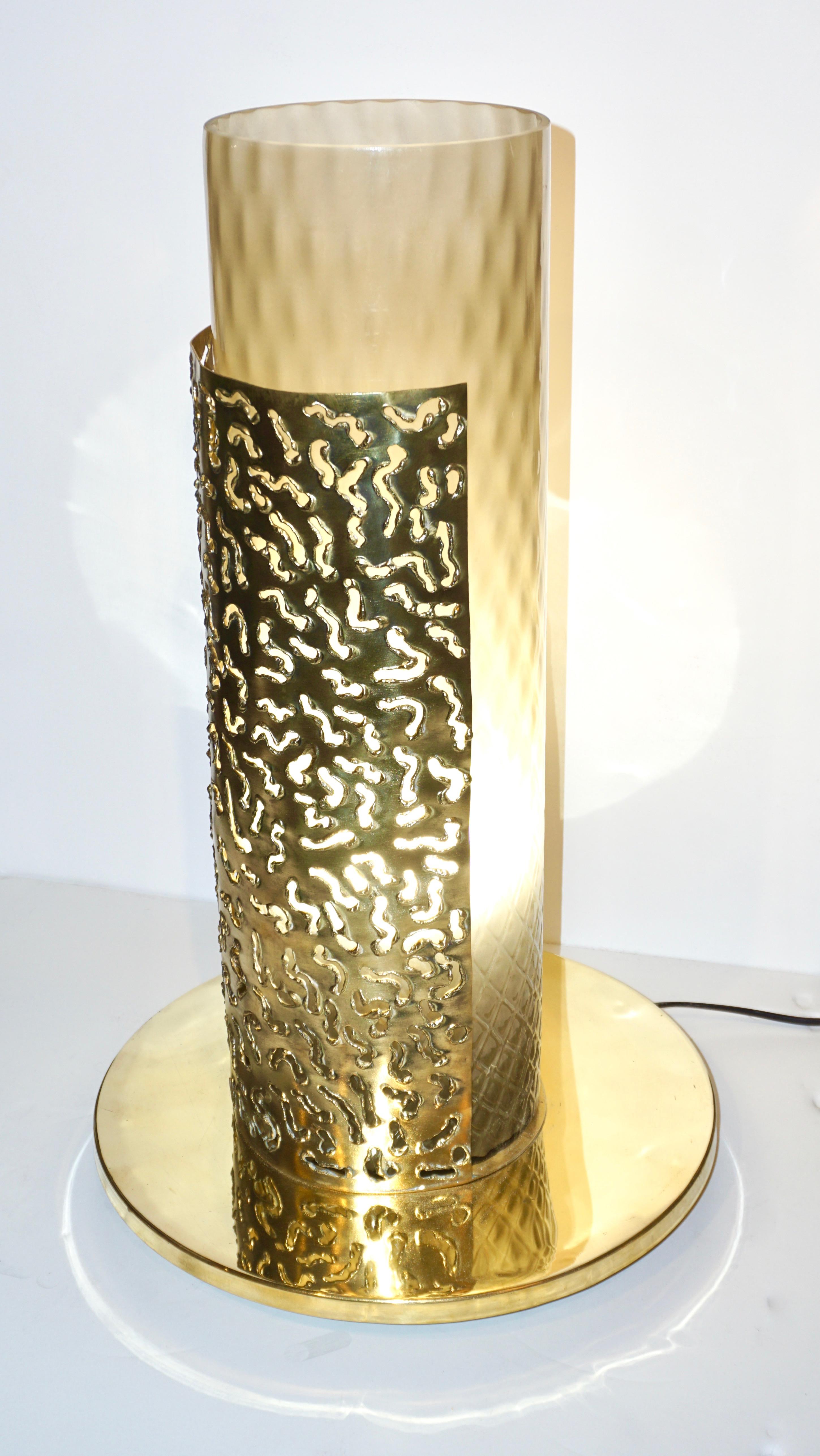 Late 1970s-early 1980s one of a kind Italian pair of modernist table lamps with an Art Deco flair. The handmade brass structure, raised on a round base with small feet, is composed of a half round shield decorated with a sculptural brass lace