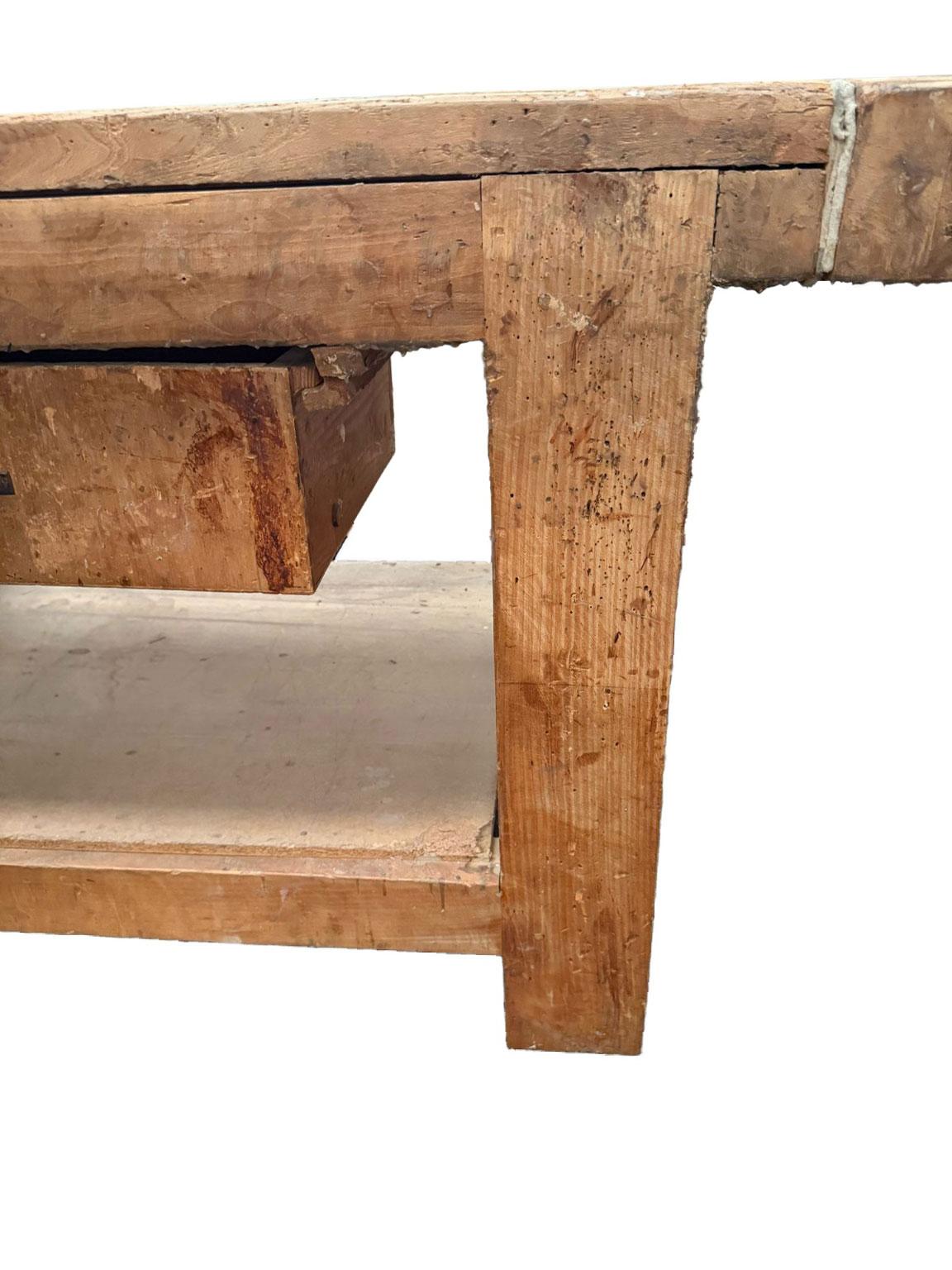 This is an original vintage carpenter’s workbench from the 1980s. Made entirely of solid wood, it retains the marks of time and craftsmanship, enhancing its authentic, rustic charm. Equipped with a functional side vise and a large work surface, it's