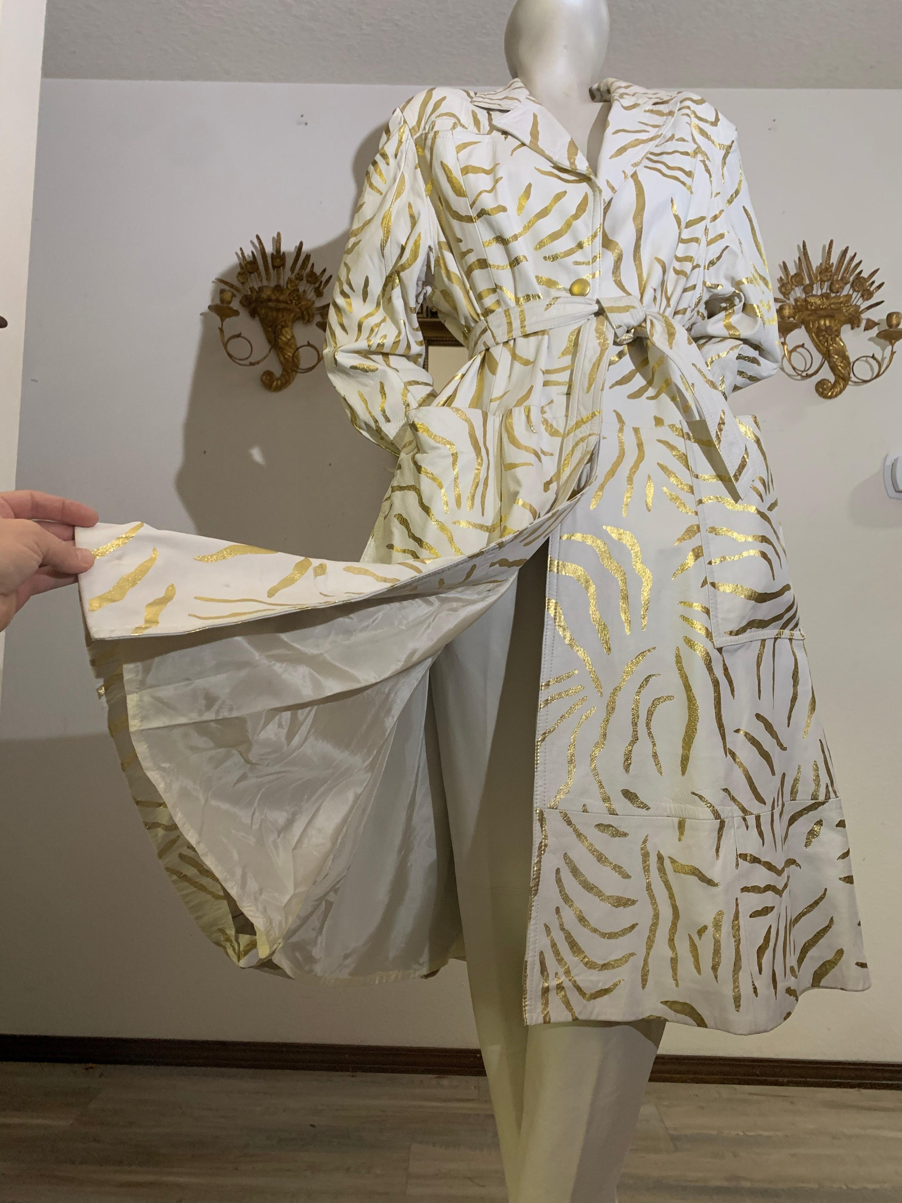 1980 Lillie Rubin White Leather Trench Coat w Gold Metallic Zebra Stripe Stencil Pattern Over-All:  Classic trench coat styling--full cut with strong shoulders and belt-defined waist. Large patch pockets, deep center back vent, gold leather buttons,