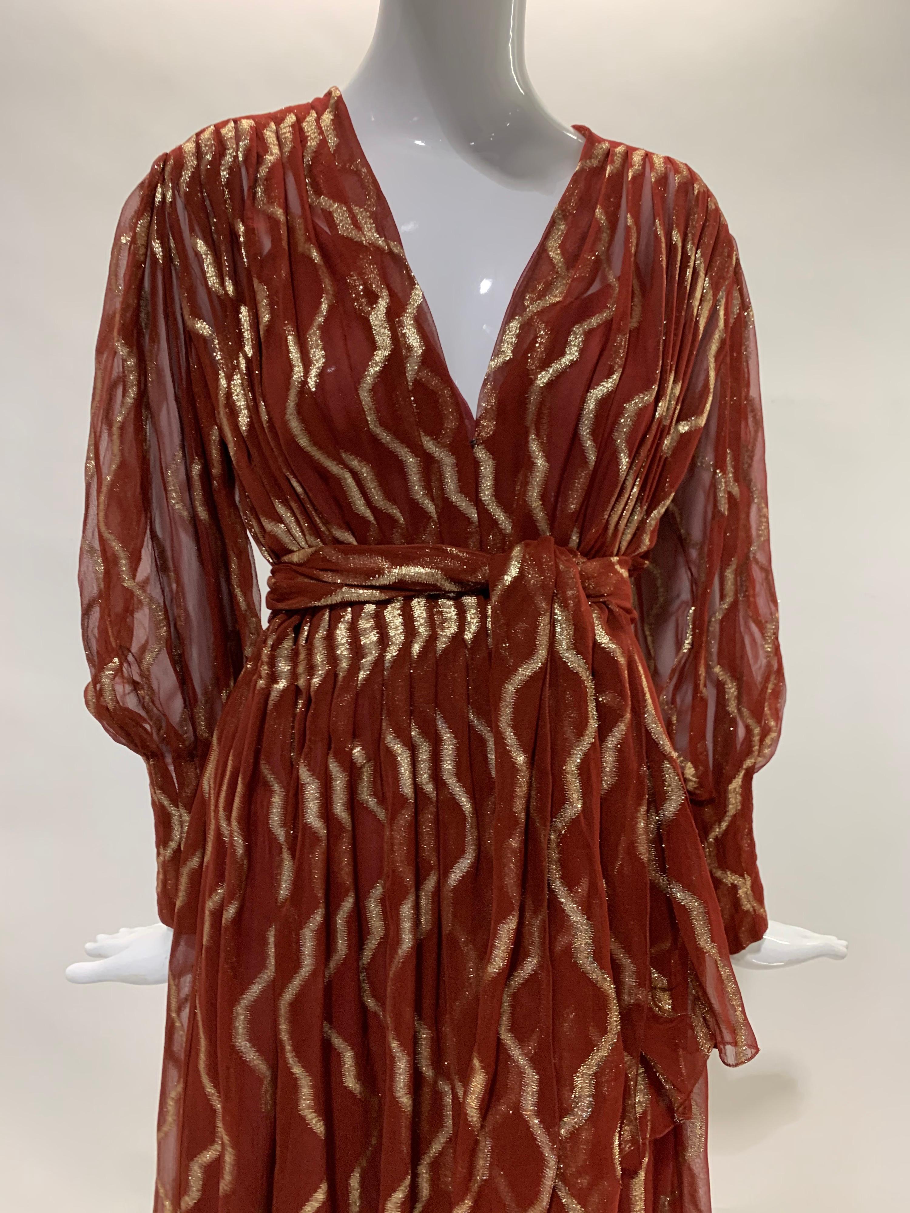 A graceful late 1970s/early 1980s Pauline Trigere carnelian-toned silk chiffon and lame pleated dress with surplice neckline and matching sash tie. Full balloon sleeves with wide zippered cuffs. Original princess-seamed silk chiffon slip with