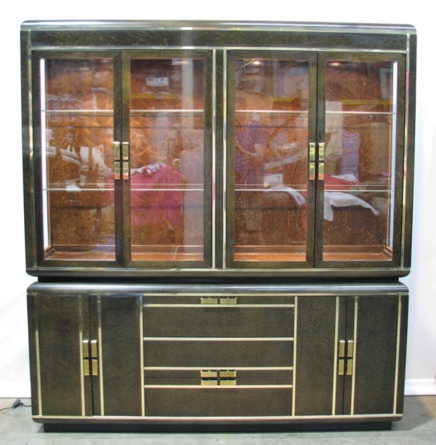 Striking sideboard/buffet with china cabinet top by high-end maker Romweber. Made in 1980, the piece exhibits the influence of that era's rediscovery of Art Deco, simple lines, streamlined curves and exotic veneers. Brass strips reinforce the