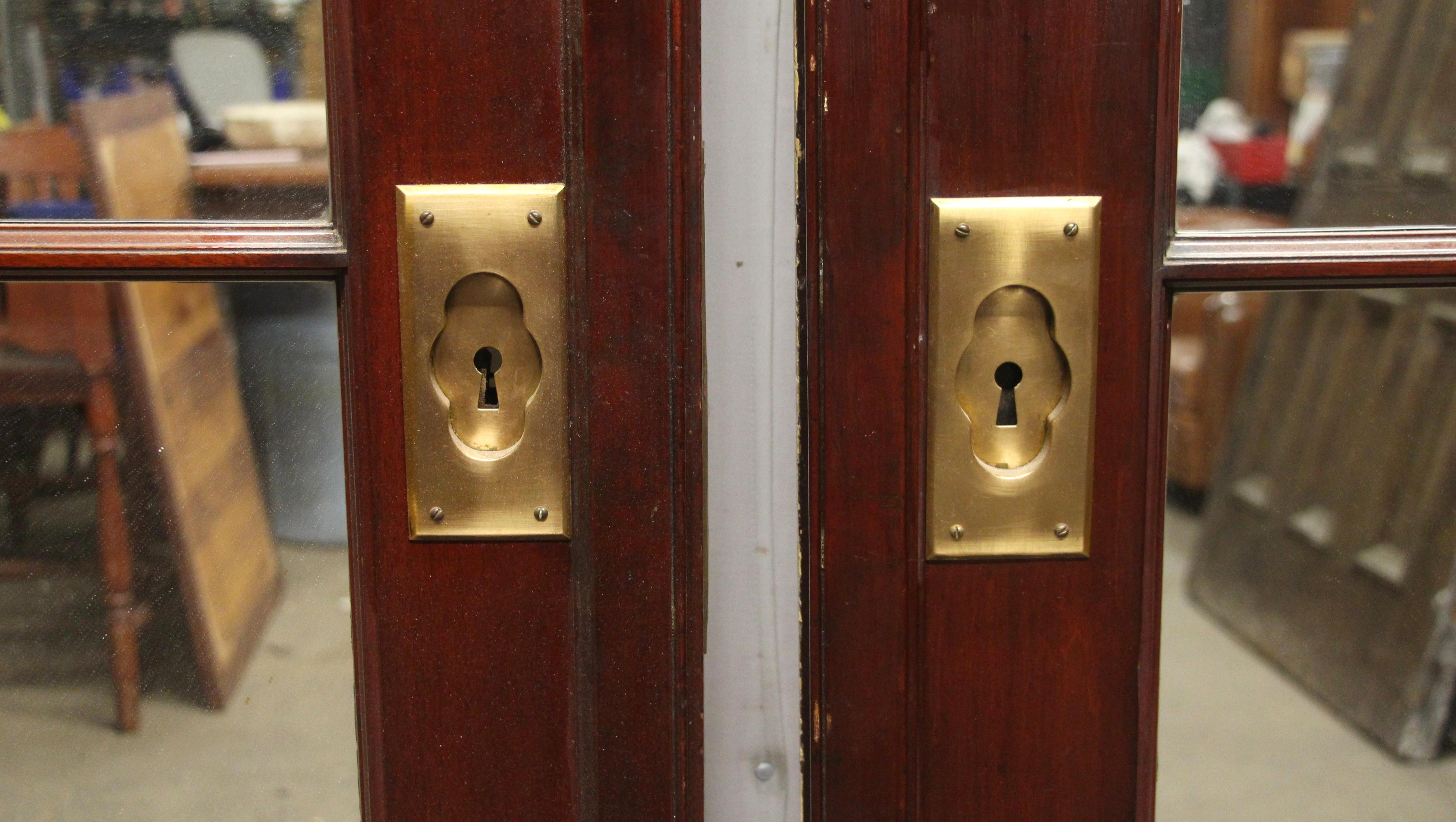 Puertas francesas dobles de caoba de los años 80 con 12 cristales de espejo y herrajes originales de bronce cepillado. Las puertas están pintadas de blanco en el lado opuesto. Precio por par. Puede verlo en nuestra sede de 400 Gilligan St, en