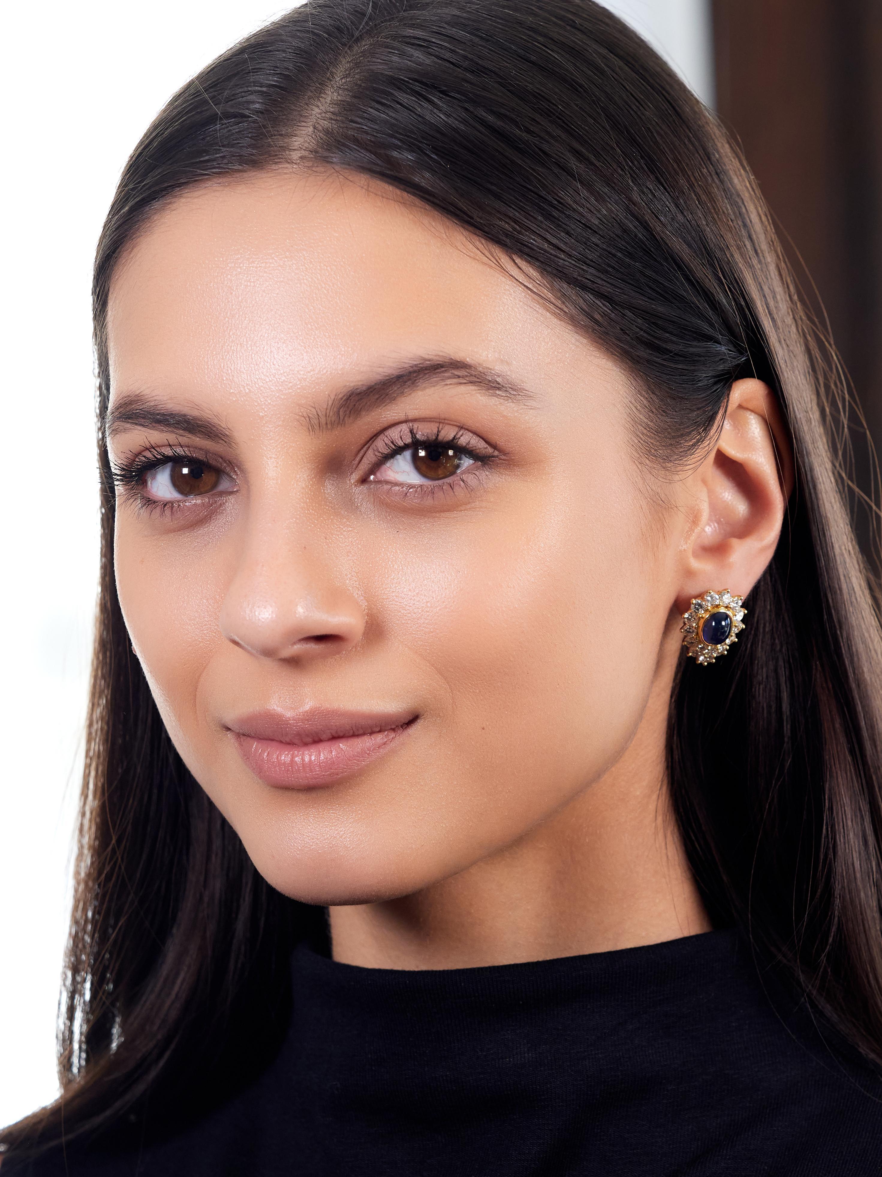 Centering sapphire sugarloaf cabochons weighing approximately 9.80 carats total
Transparent medium blue in color and bezel set with clustered diamond surround
Round brilliant cut and weighing approximately 4.76 carats total
G color with VS2 clarity