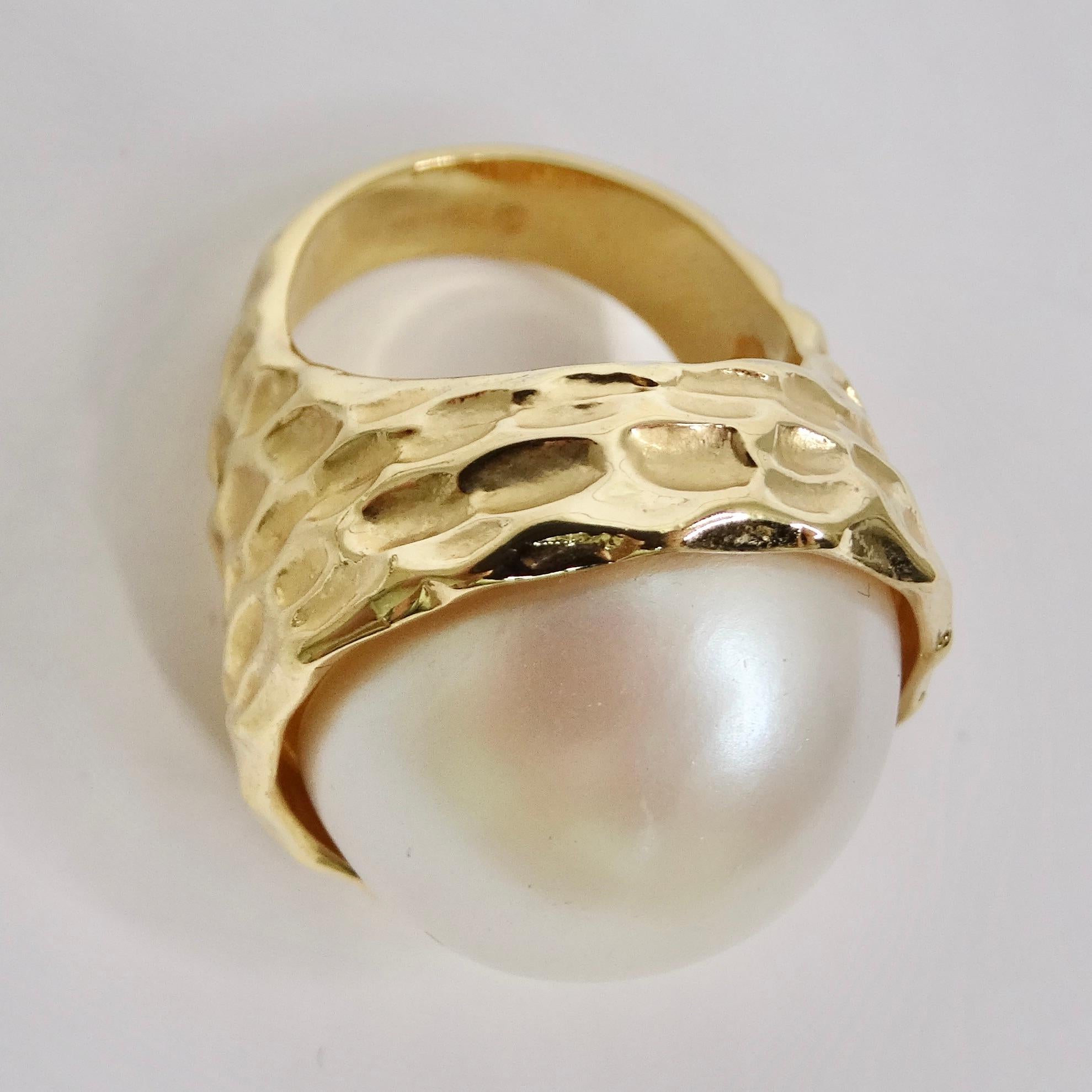 Elevate your style with our 1980s 14K Gold Plated Synthetic Pearl Ring, a captivating and luxurious statement piece that exudes elegance and sophistication. At its center, this ring boasts a stunning synthetic pearl of substantial size. Its lustrous
