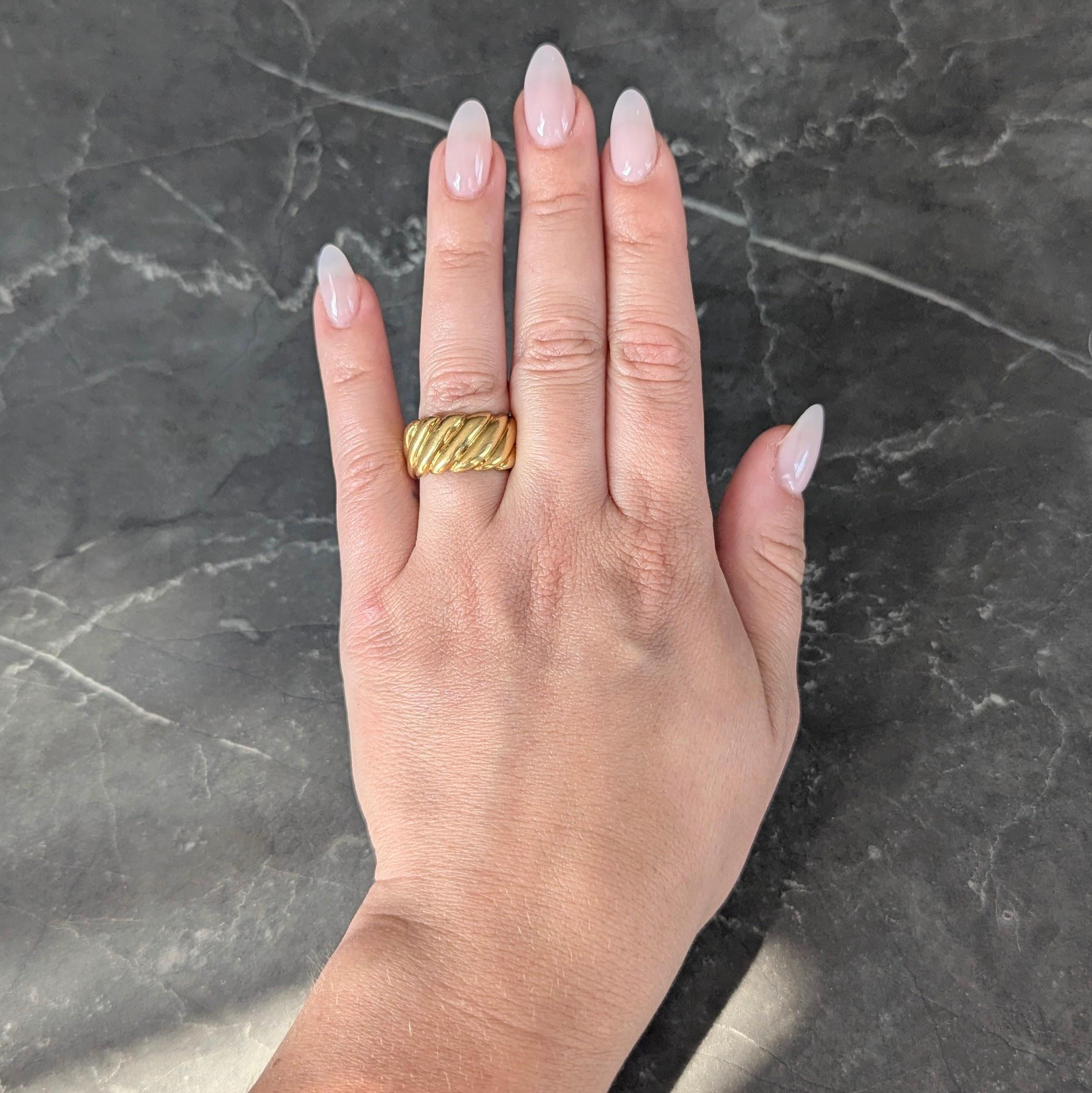 Designed as a wide band ring with deeply grooved segments
Puffed and depicting a twist motif
With undulating edges
Stamped for 18 karat gold
Circa: 1980's
Ring Size: 6 1/4 and not sizable
Measures north to south 10.2 mm and sits 2.0 mm high
Total