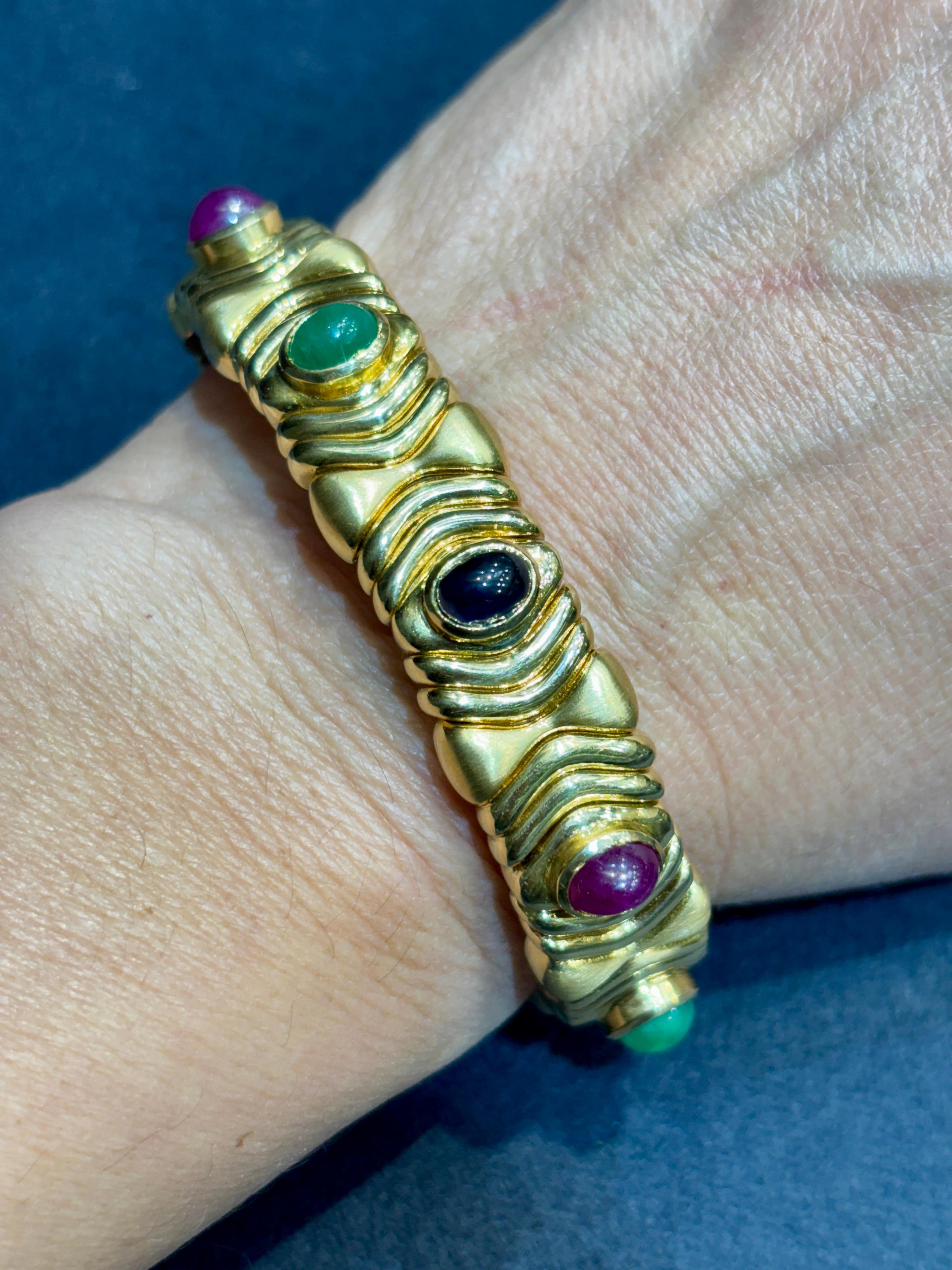 This classic 1980s Bulgari bangle is made of 18k gold and adorned with cabochon rubies, sapphires and emeralds. The bracelet can expand to fit wrists that measure 16-18cm in circumference.