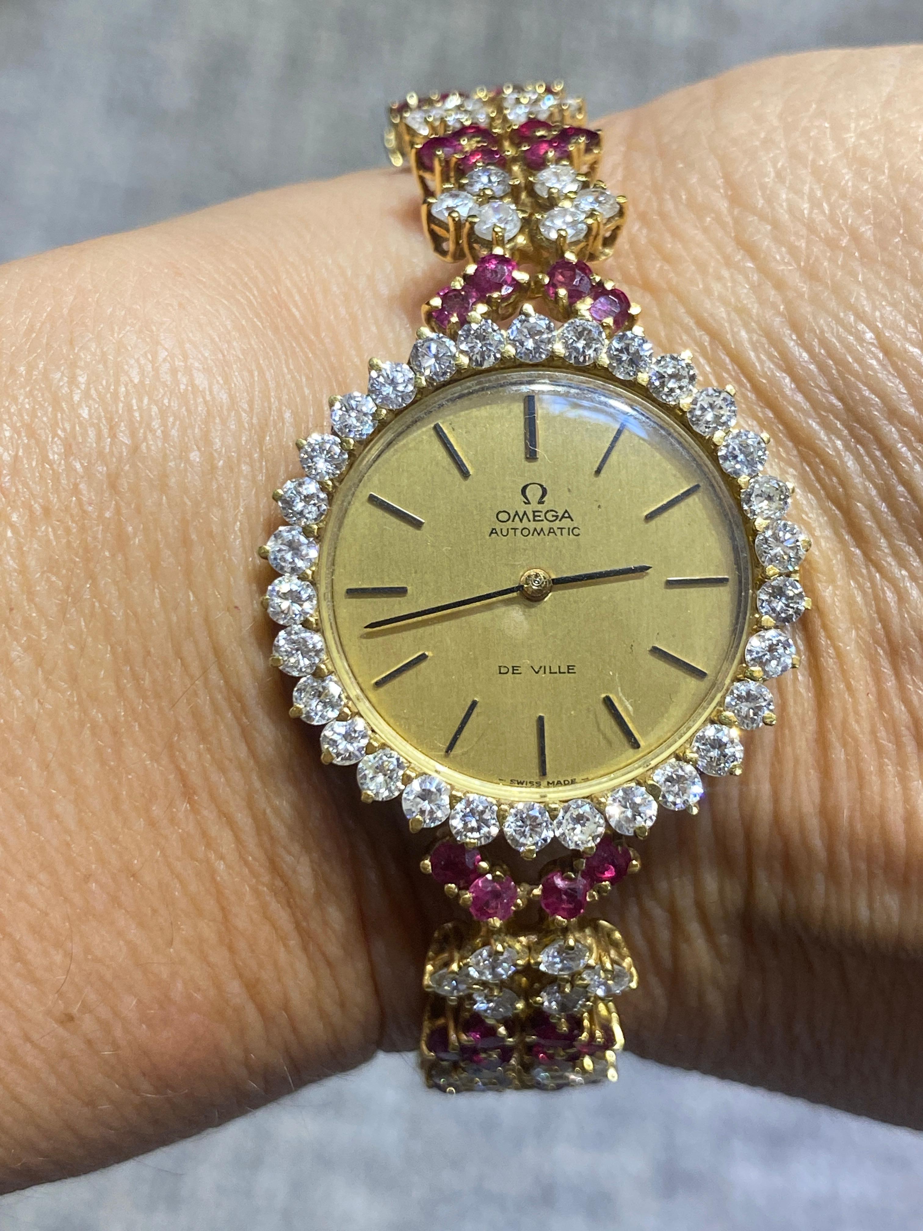 This 1980s 18k gold Omega de Ville watch is adorned with approximately 5 carats of round cut diamonds and 3 carats of round cut rubies. The face measures 28mm and the bracelet 11mm in width. It is an elegant addition to any collection.