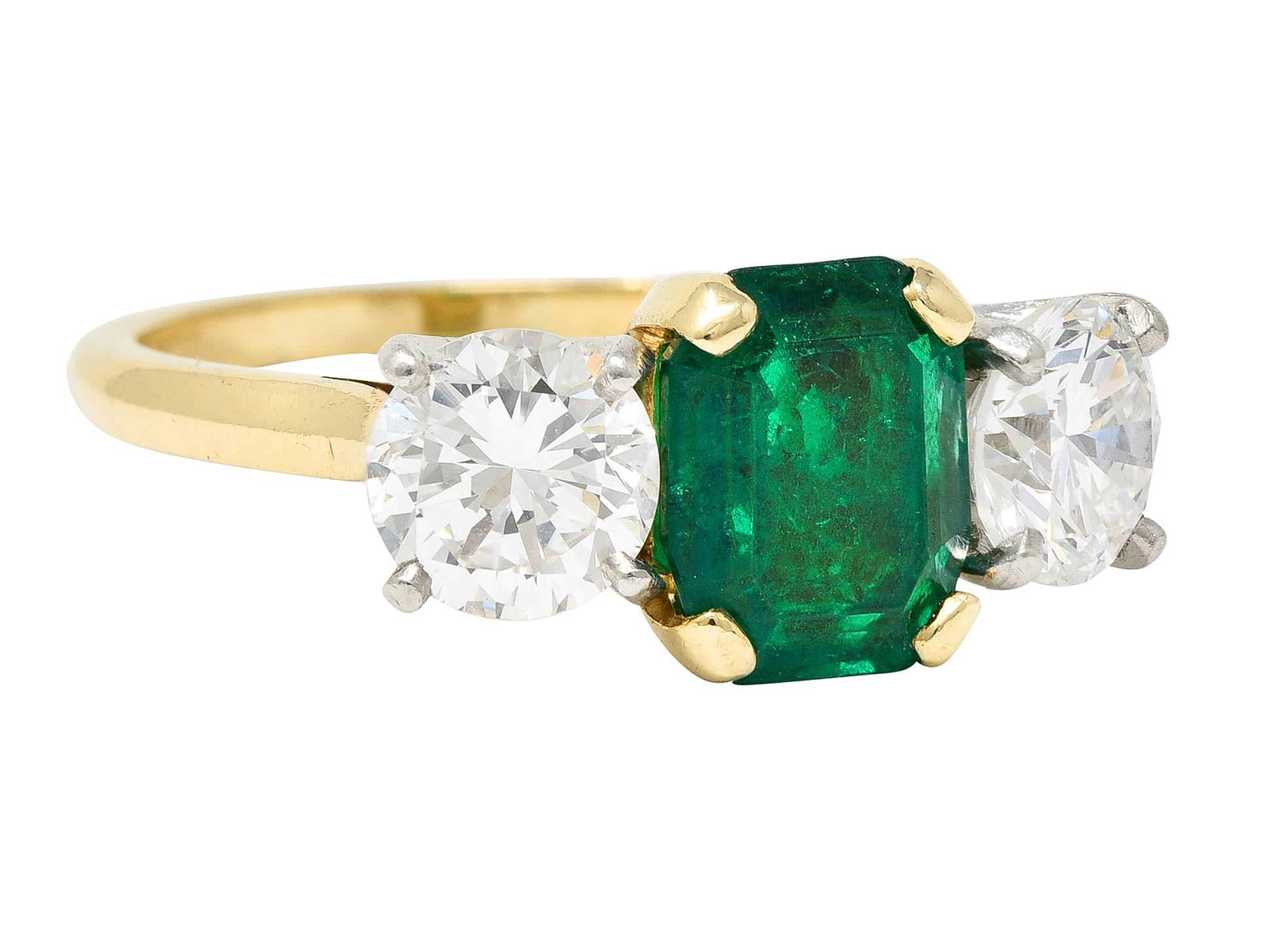 Centering an emerald cut emerald weighing approximately 1.67 carats - transparent medium green in color
Natural Colombian in origin with F2 moderate clarity enhancement
Prong set in a gold basket and flanked by round brilliant cut diamonds
Weighing