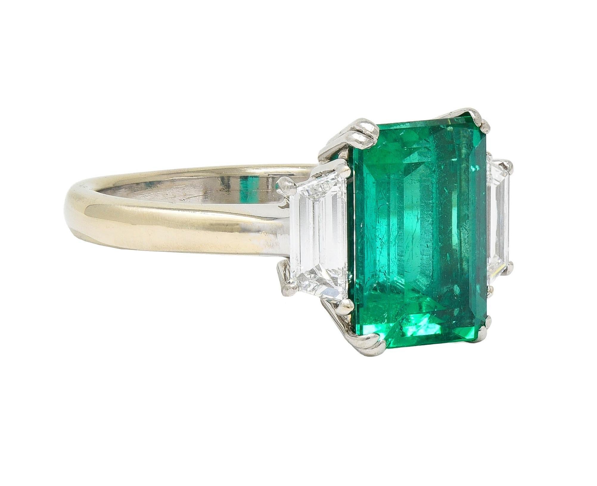 Centering and emerald cut emerald weighing 2.99 carats total - transparent medium green in color
Natural Colombian in origin with minor clarity enhancement - set with split prongs in platinum basket
Flanked by tapered baguette cut diamonds weighing