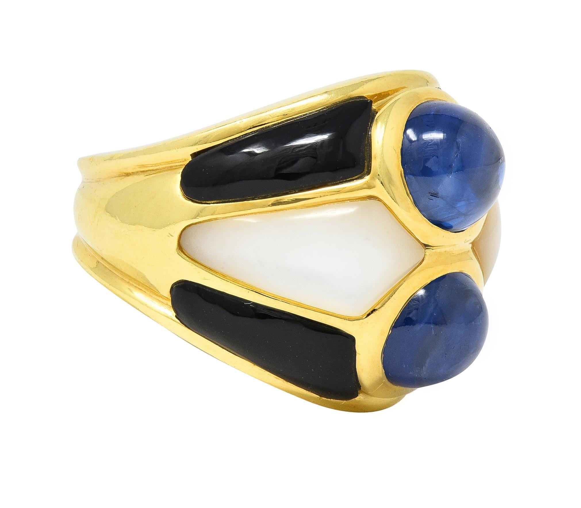 Featuring two oval-shaped sapphire cabochons bezel set north to south 
Weighing approximately 8.80 carats total - translucent medium blue
With geometric motif segmented pattern surround 
Inlaid with onyx and mother-of-pearl cabochons
Opaque black