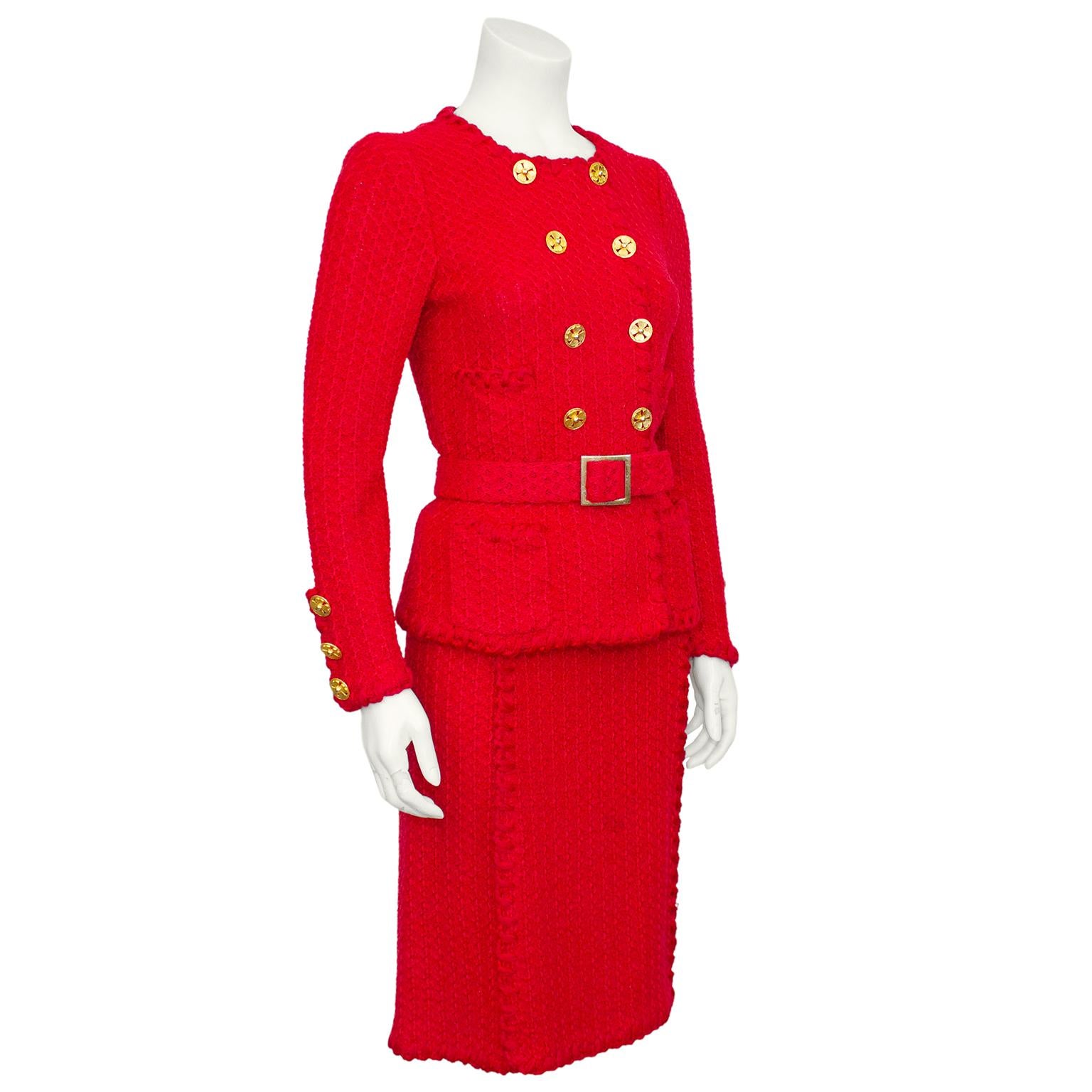 Adolfo red wool knit skirt suit from the 1980s. Double breasted jacket is collarless with gold tone clover buttons and four patch pockets. Optional belt can be worn at waist of jacket. Skirt is classic high waisted with a very slight a line shape.