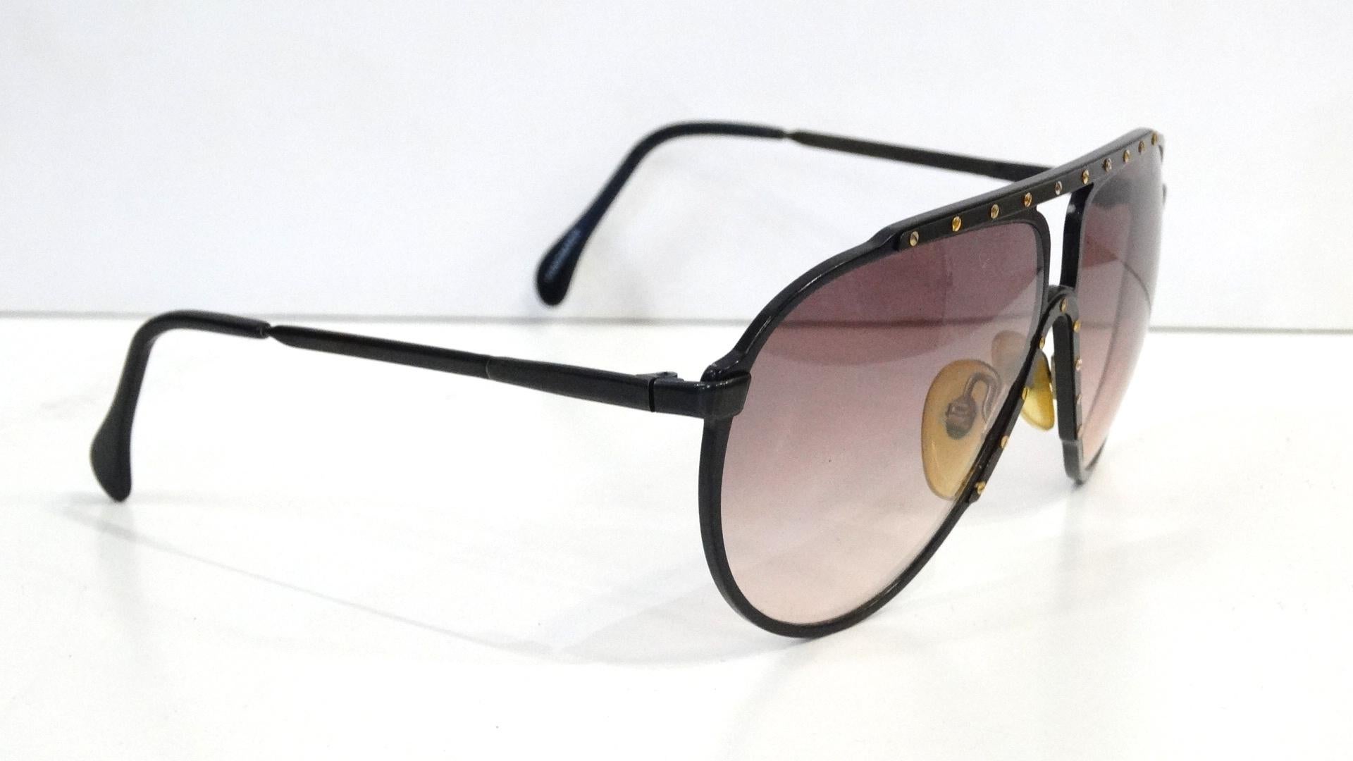 The Most Amazing Sunglasses! Circa late 1980s, these Alpina M1 sunglasses are an aviator style and feature a black metal frame with gold plated flat head screws on the top bar and down the bridge. Dark brown/black gradient lenses. The most killer
