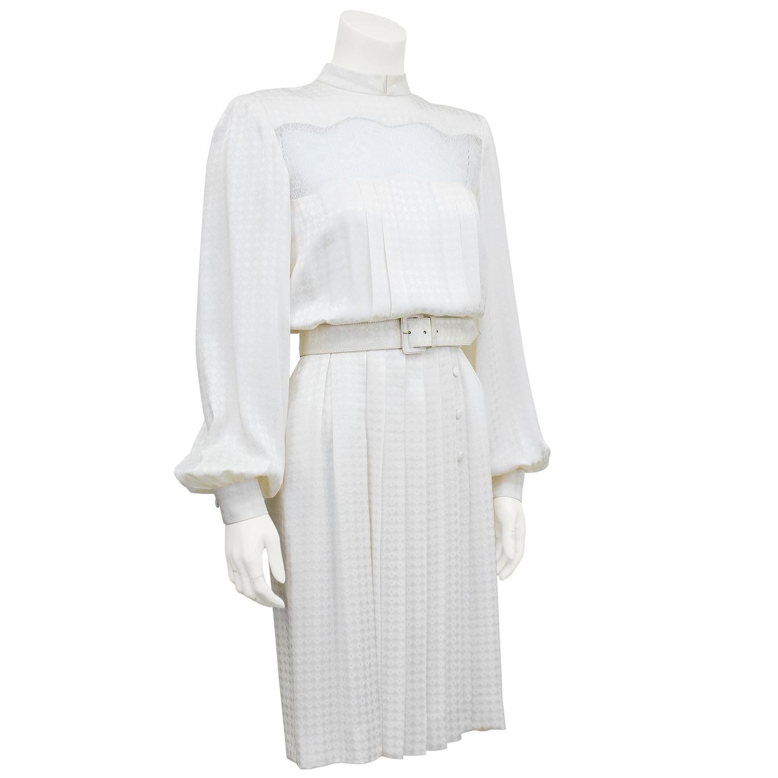 1980s Andre Laug cream silk jacquard dress. Mock turtleneck, oversized bishop sleeves and pleated bodice and skirt. Belted at waist with matching jacquard pattern. White lace cut out detail above the bust and upper back. White lining. Good vintage