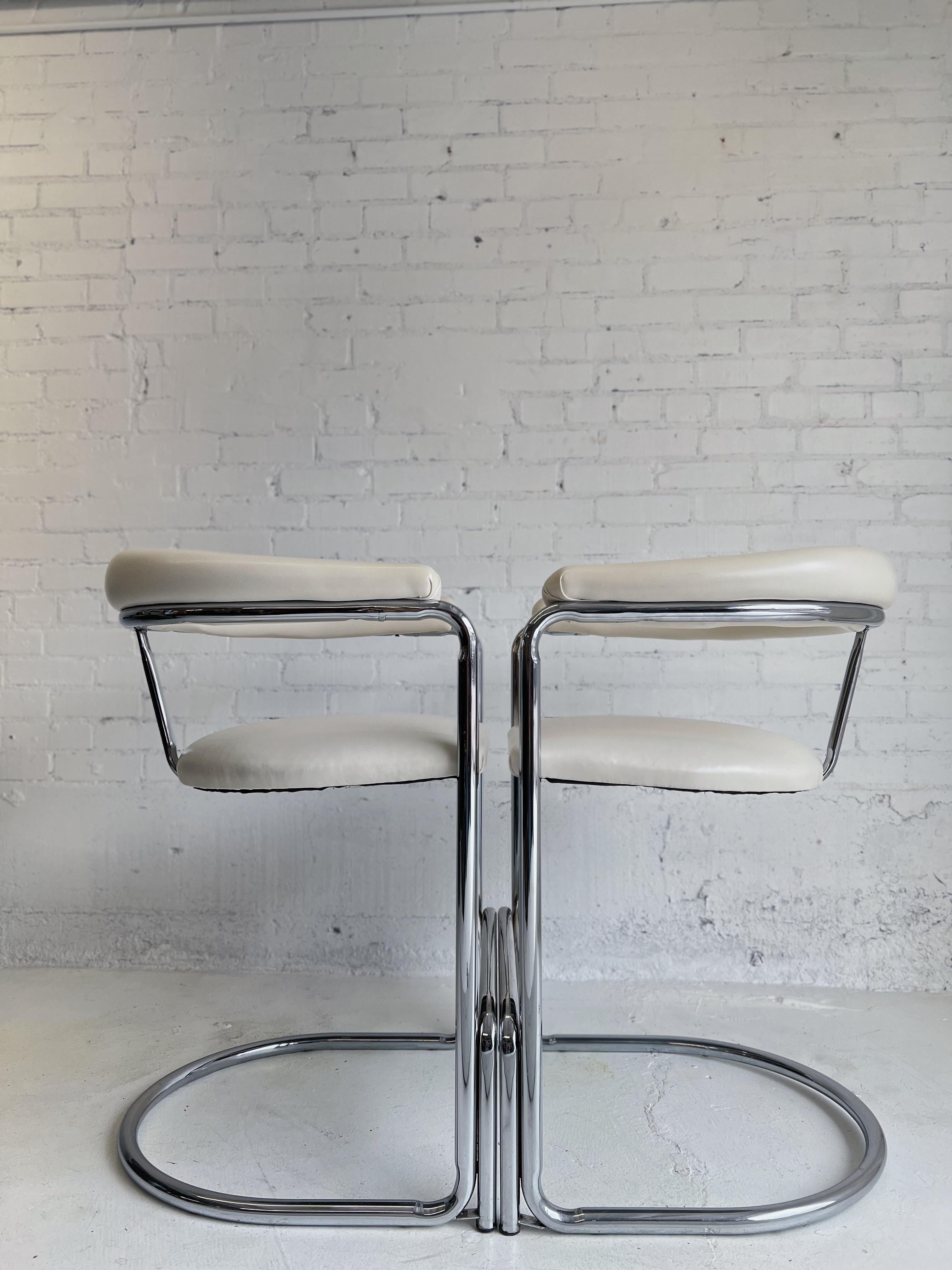 Chrome bar stools designed by Anton Lorenz for Thonet in 1929. Stools feature off-white faux leather upholstered seat and backrest with chrome-plated tubular steel frame and stabilizing foot rest bars. Stools are in good vintage condition with minor