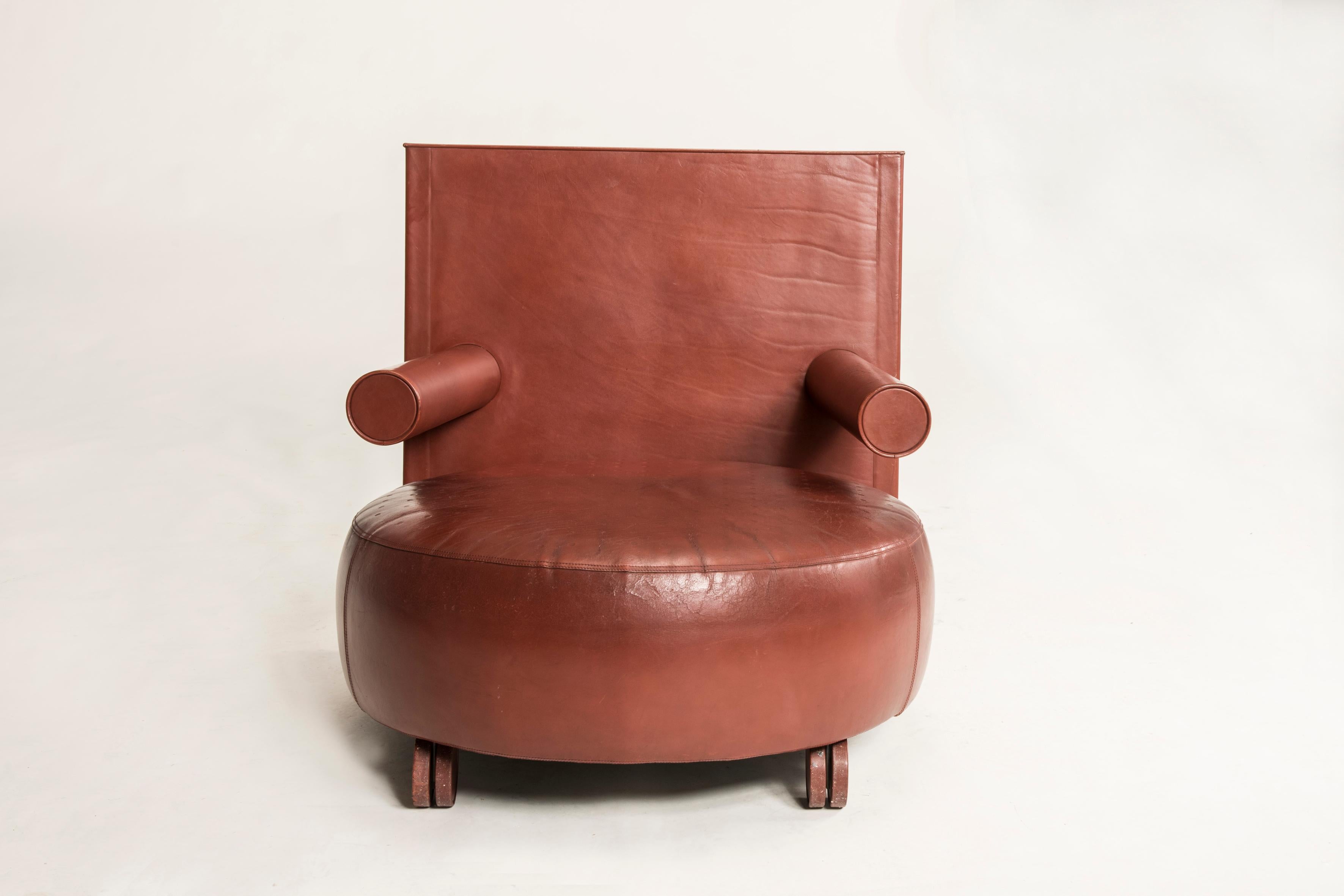 Brown cow leather armchair designed by Antonio Citterio, produced by B&B Italia / C&B Italia, circa 1980s. Rounded Seat and squared backrest make this piece an Iconic piece in Memphis style. Marked and signed, features a paper sticker under the seat