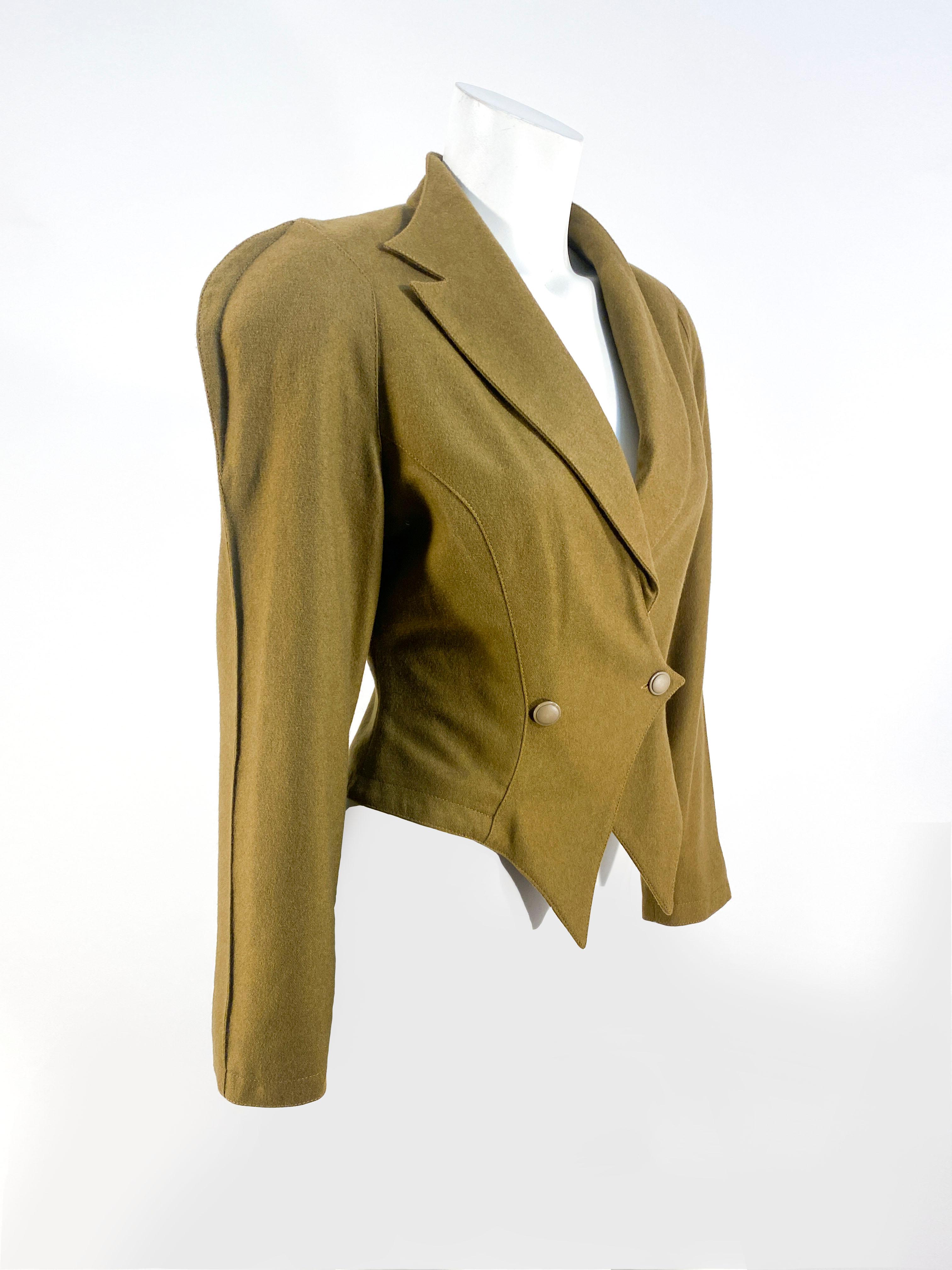 1980s army green/brown wool jacket featuring sharp finned shoulders, a contrasting shawl/peaked lapel collar, severely double breasted point darts that meet past the waist, and padded shoulders. The exaggerated silhouette is prevalent for the time