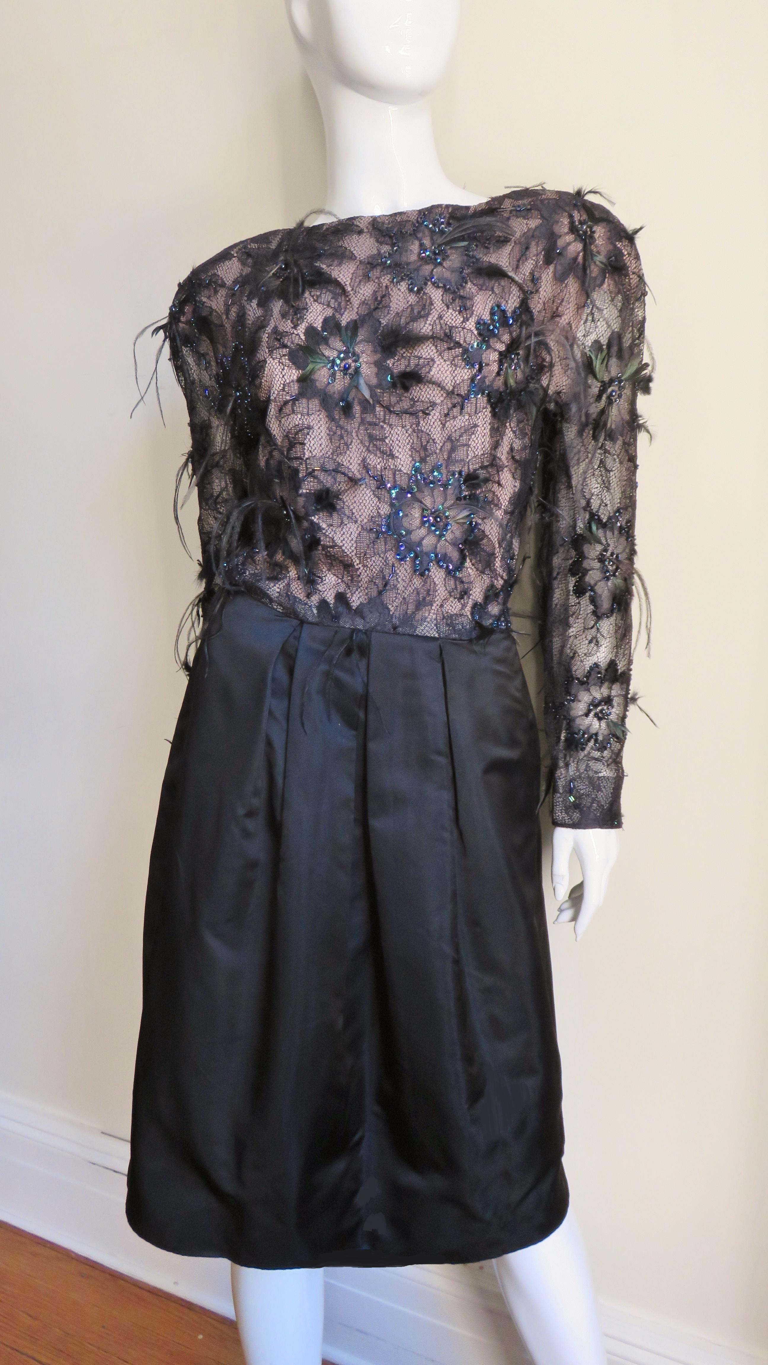 A gorgeous black silk and lace dress by Arnold Scassi.  It has a nude lined black flower lace bodice which is highlighted with black glass carnival beads and sequins plus a smattering of ostrich feathers of varying lengths.  The skirt in contrast,